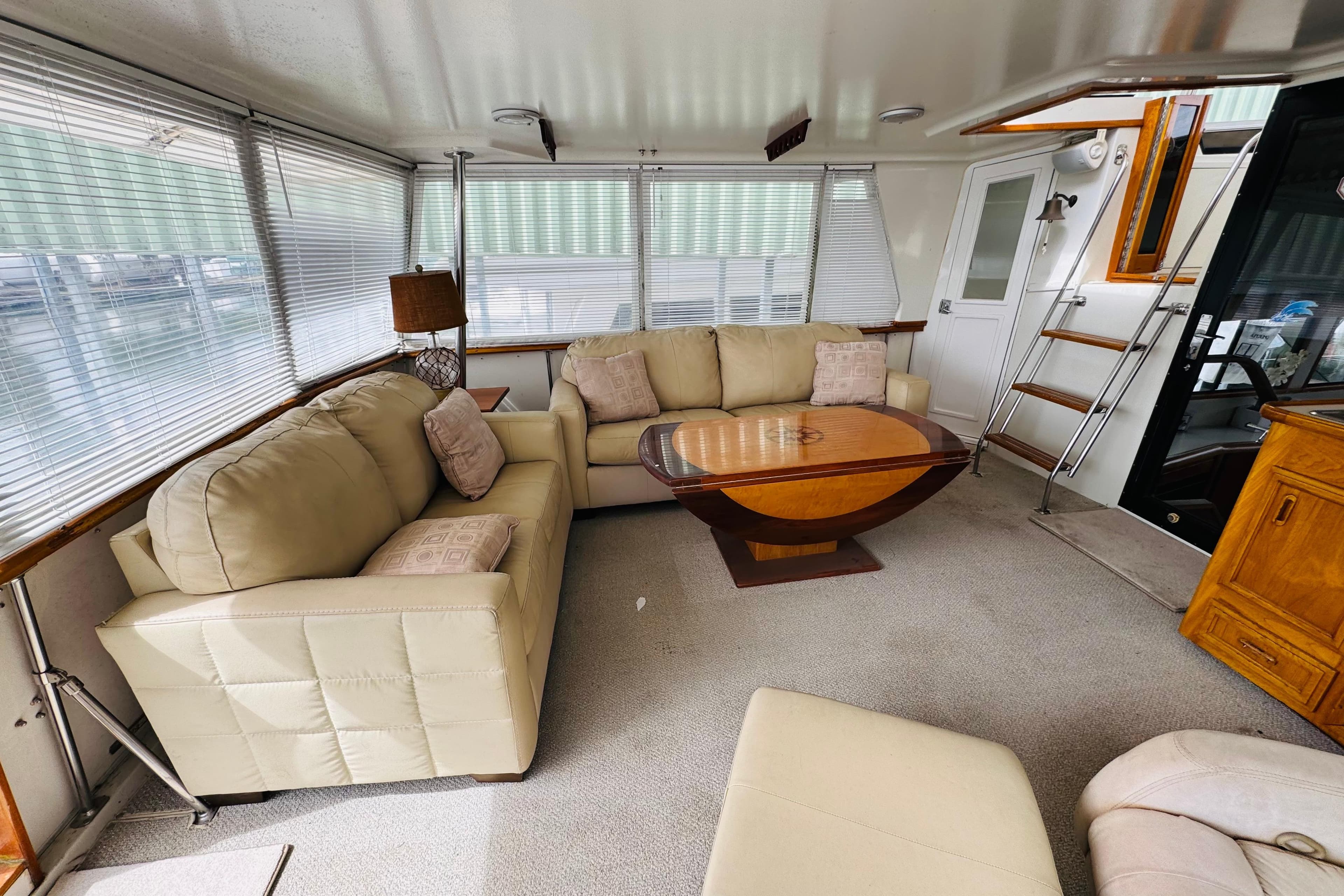 Luxurious interior of 1991 Californian 55 Cockpit Motor Yacht with beige sofas and wooden table.