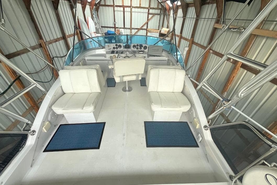 1976 Uniflite 32 Sport Sedan interior with white seating and control panel in a boathouse.