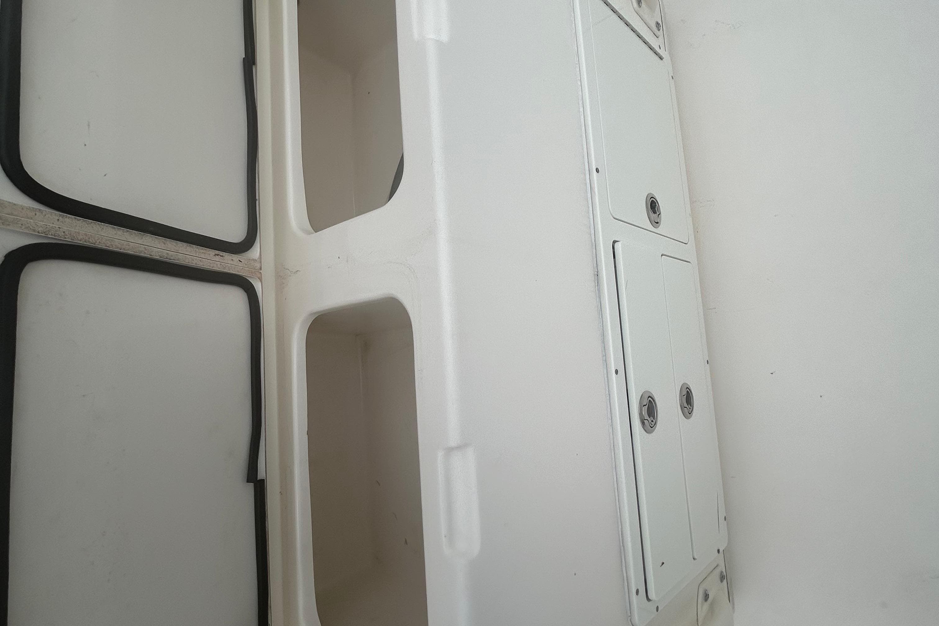 2016 Cobia 296 Center Console storage compartments and hatches, white interior view.