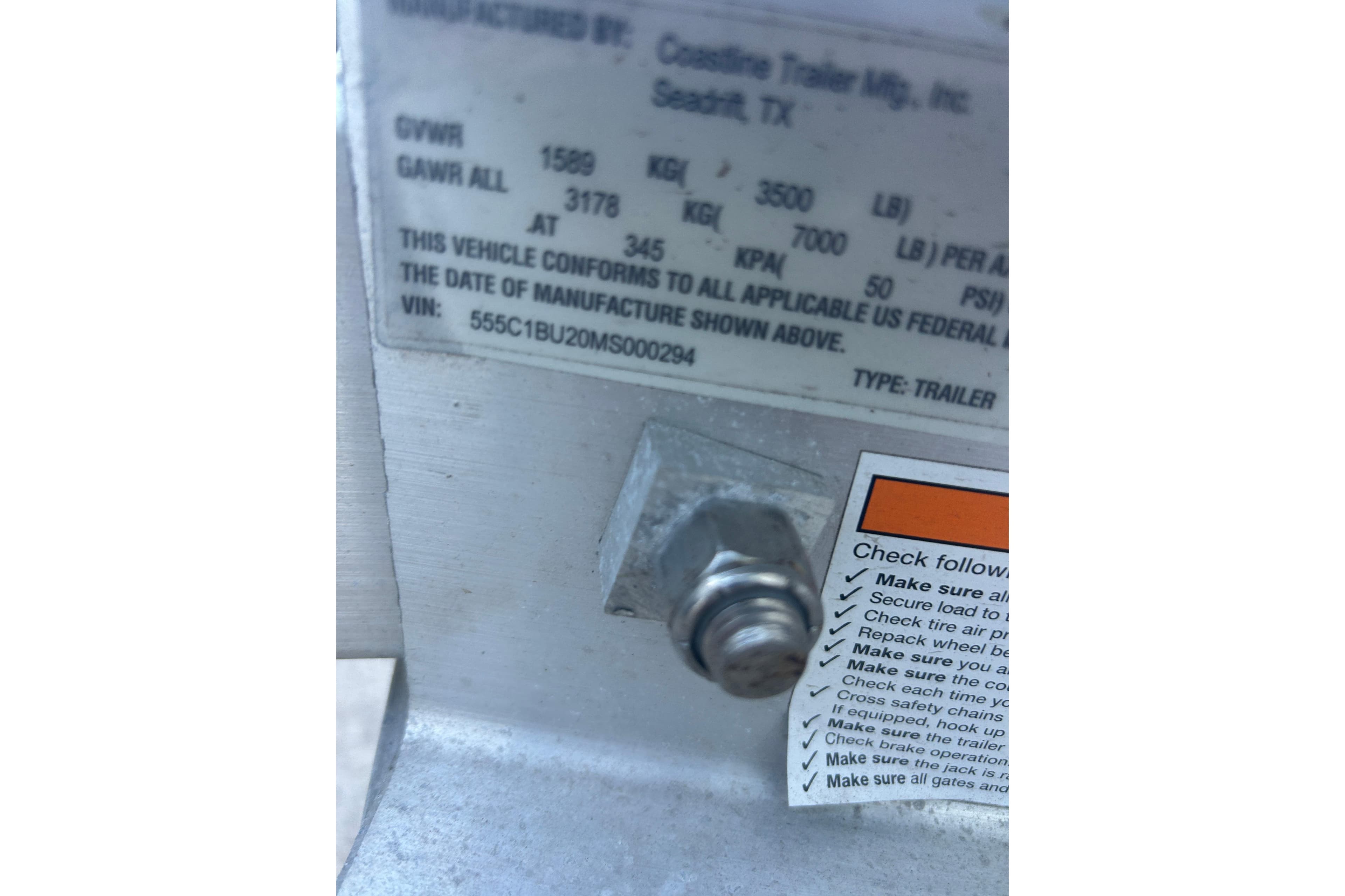 Label on trailer with specifications and safety checklist, featuring a visible bolt.