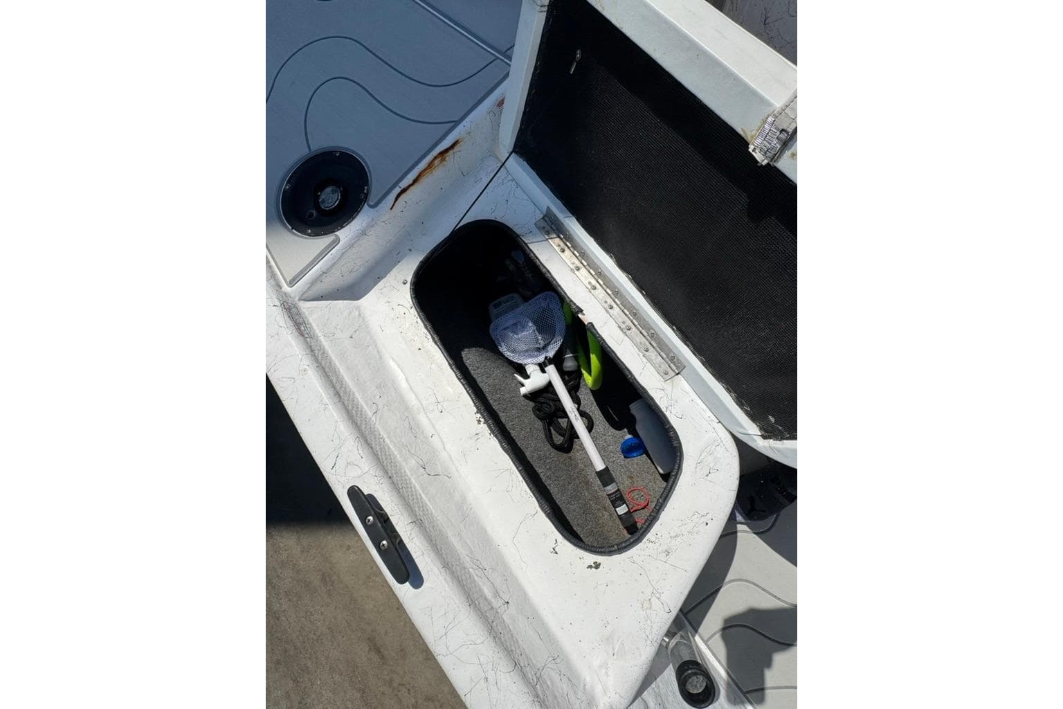 Open storage compartment on 2005 Kenner 21 VX boat, containing fishing gear and accessories.