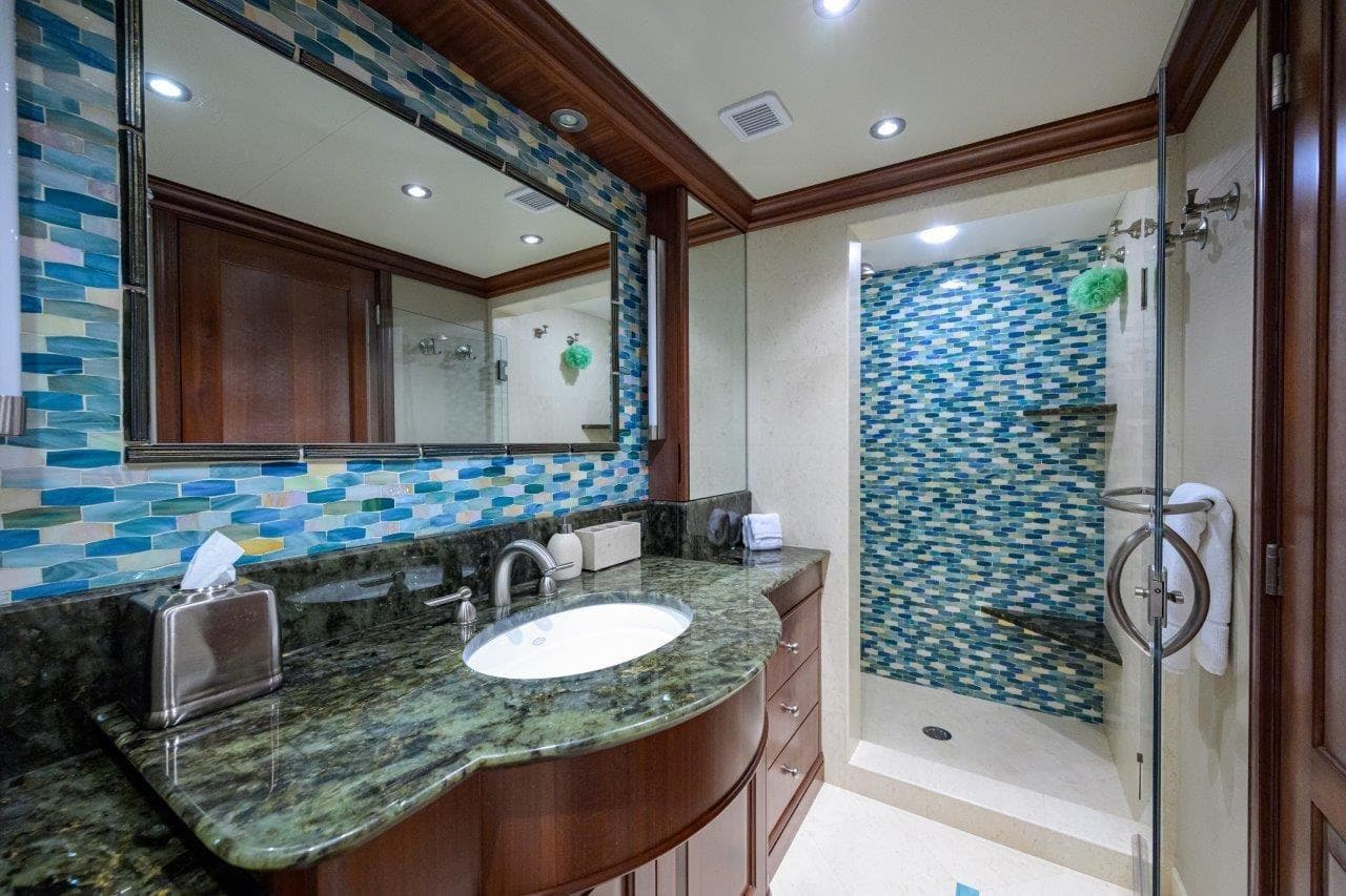 Luxurious yacht bathroom with mosaic tiles, granite countertop, and glass shower in 2011 C & G Boatworks Explorer.