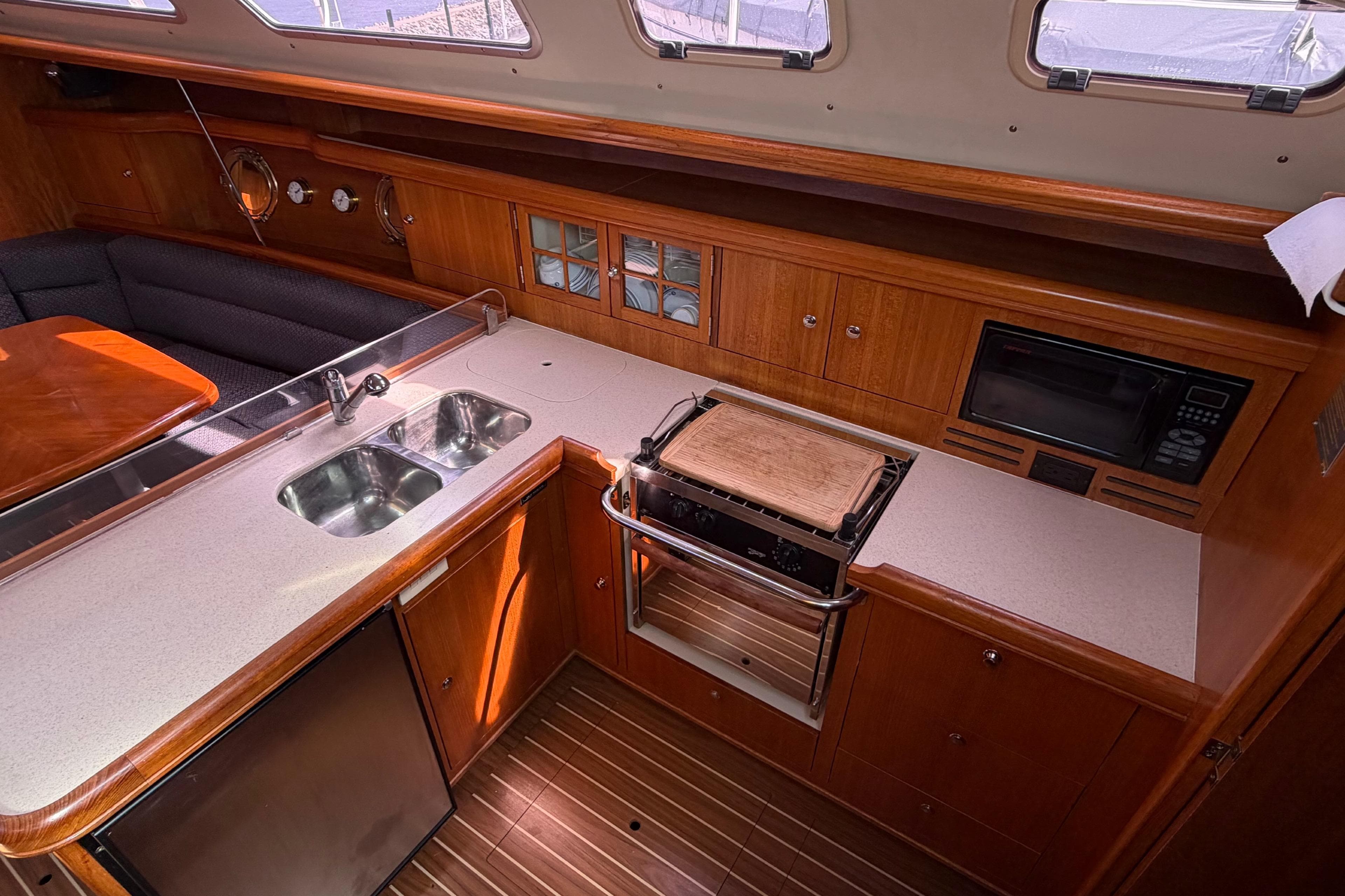 2005 Hunter 38 yacht interior kitchen with wood cabinetry, dual sink, stove, and microwave.