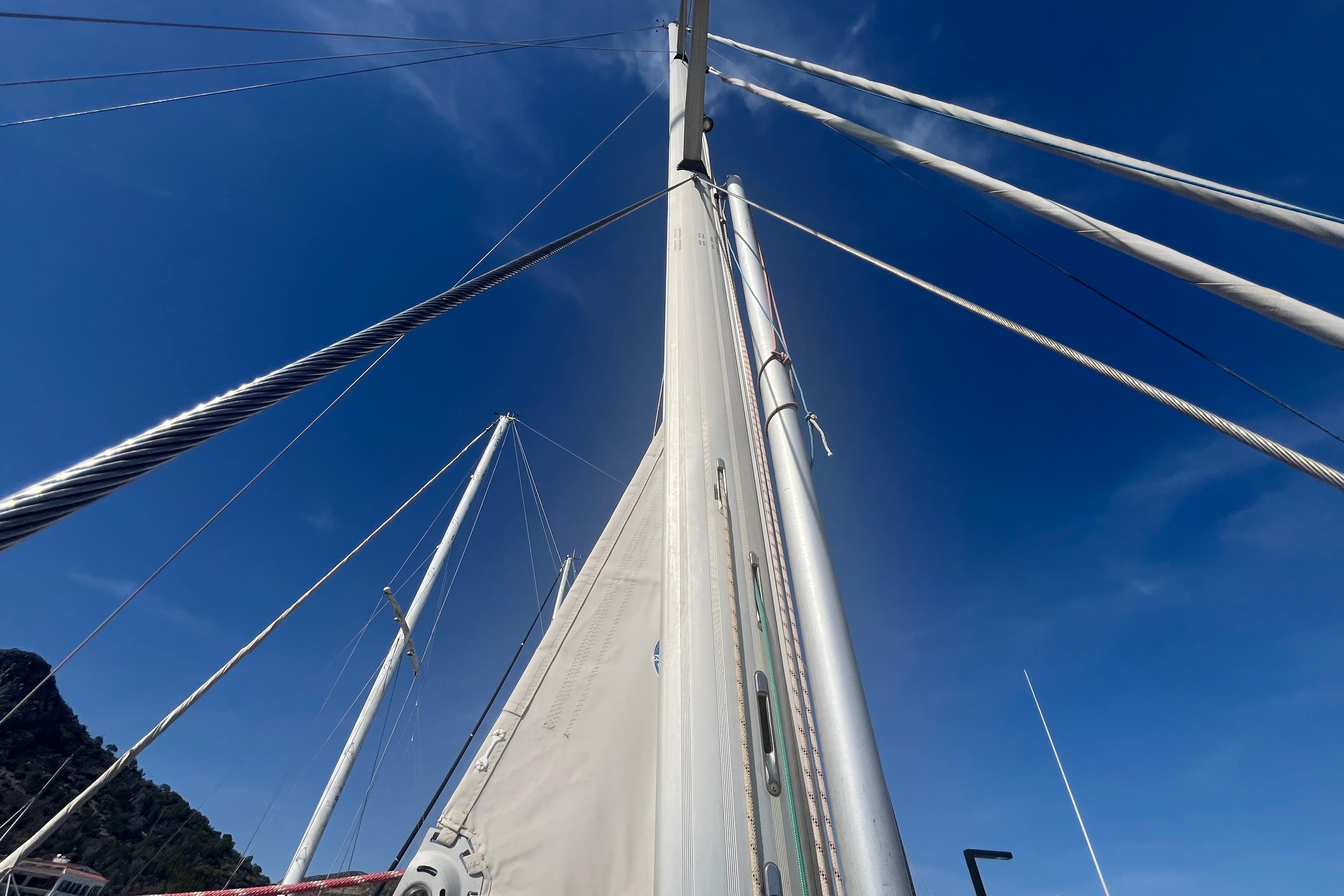 Sailboat mast and rigging of 1995 Belliure 41 against clear blue sky.