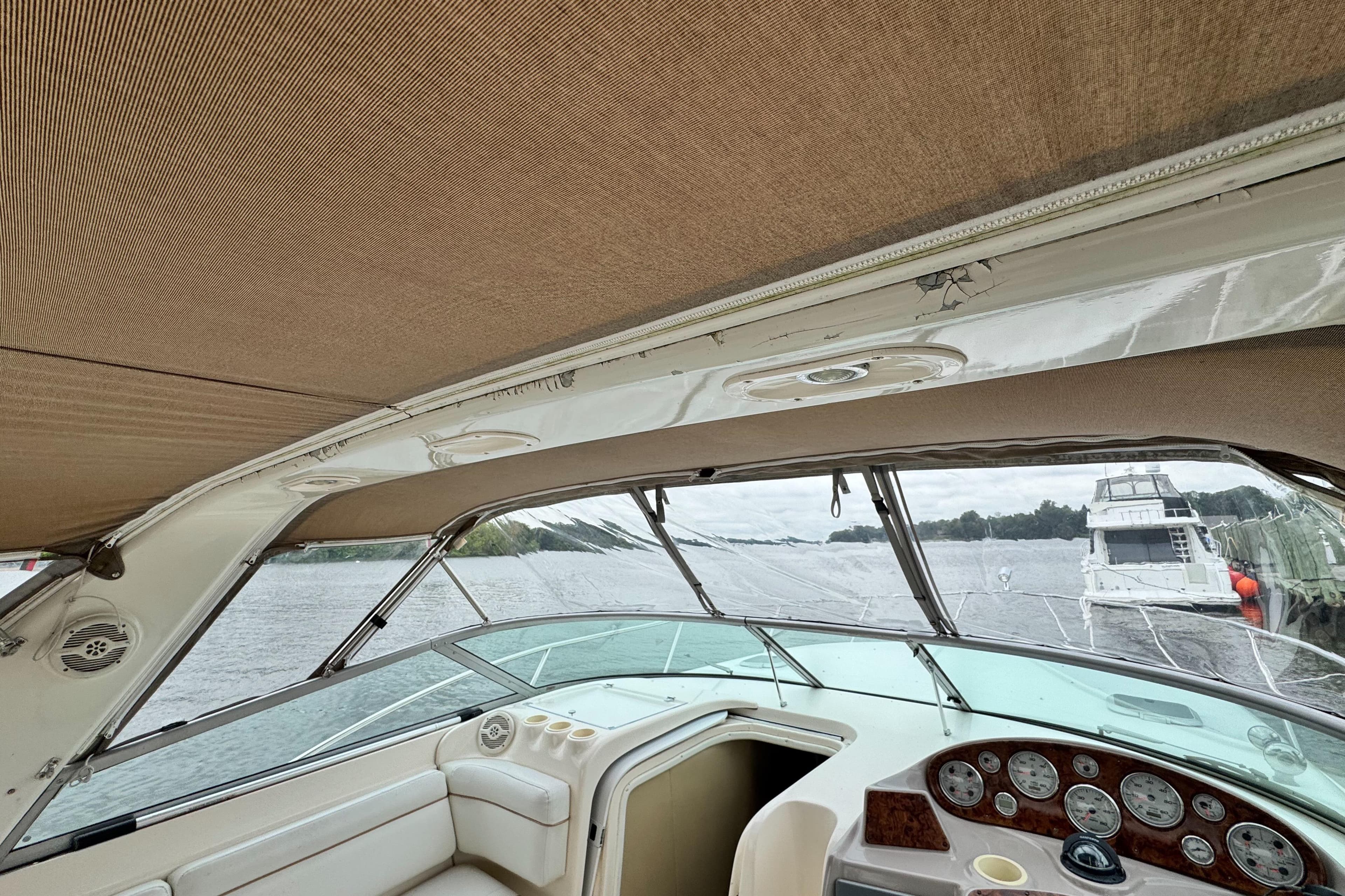 2005 Rinker Fiesta Vee 342 boat interior with dashboard and canopy, docked by the water.
