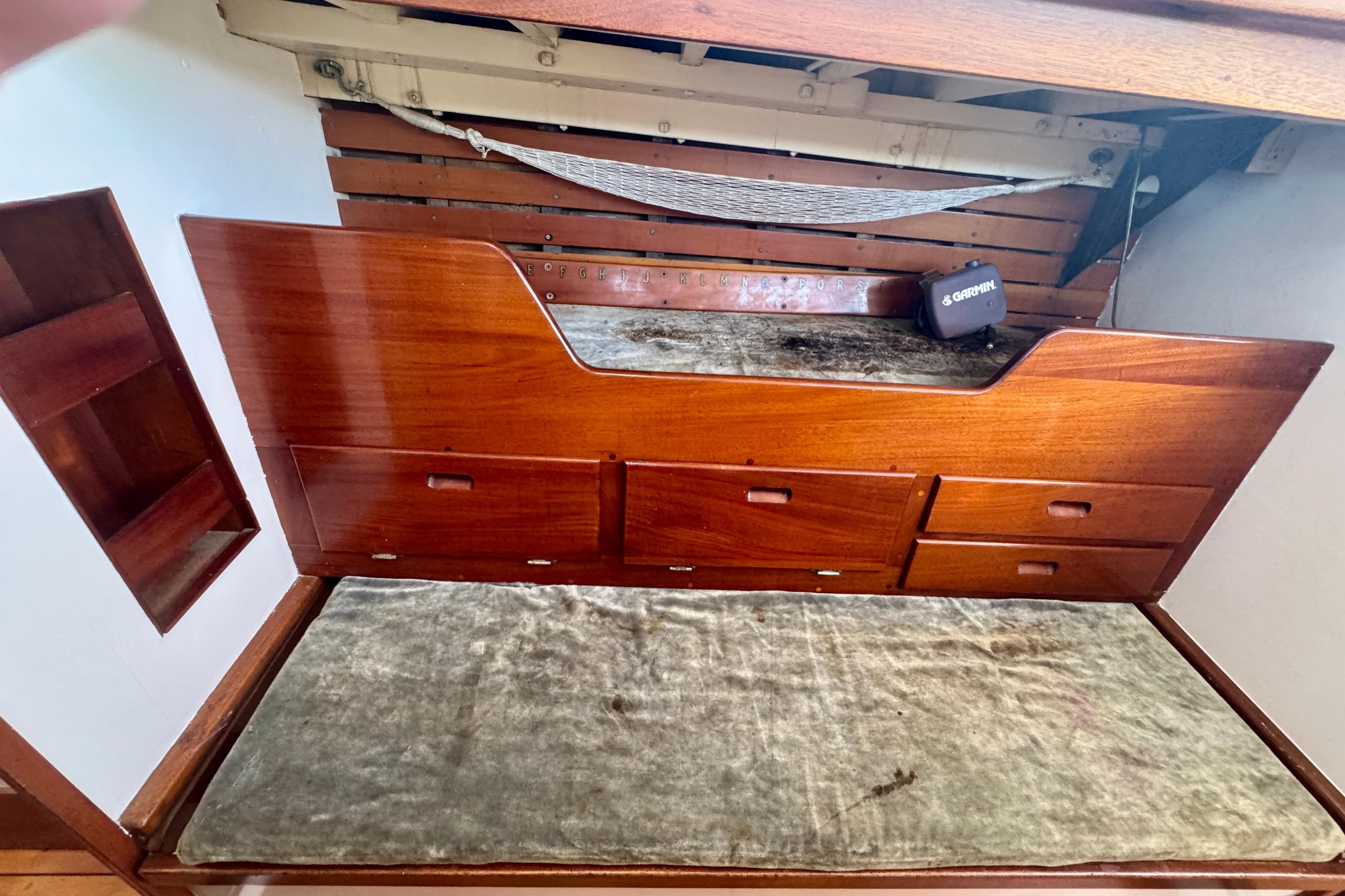 Wooden interior of a 1946 Phillip Rhodes 42 boat with storage drawers and a cushioned bench.
