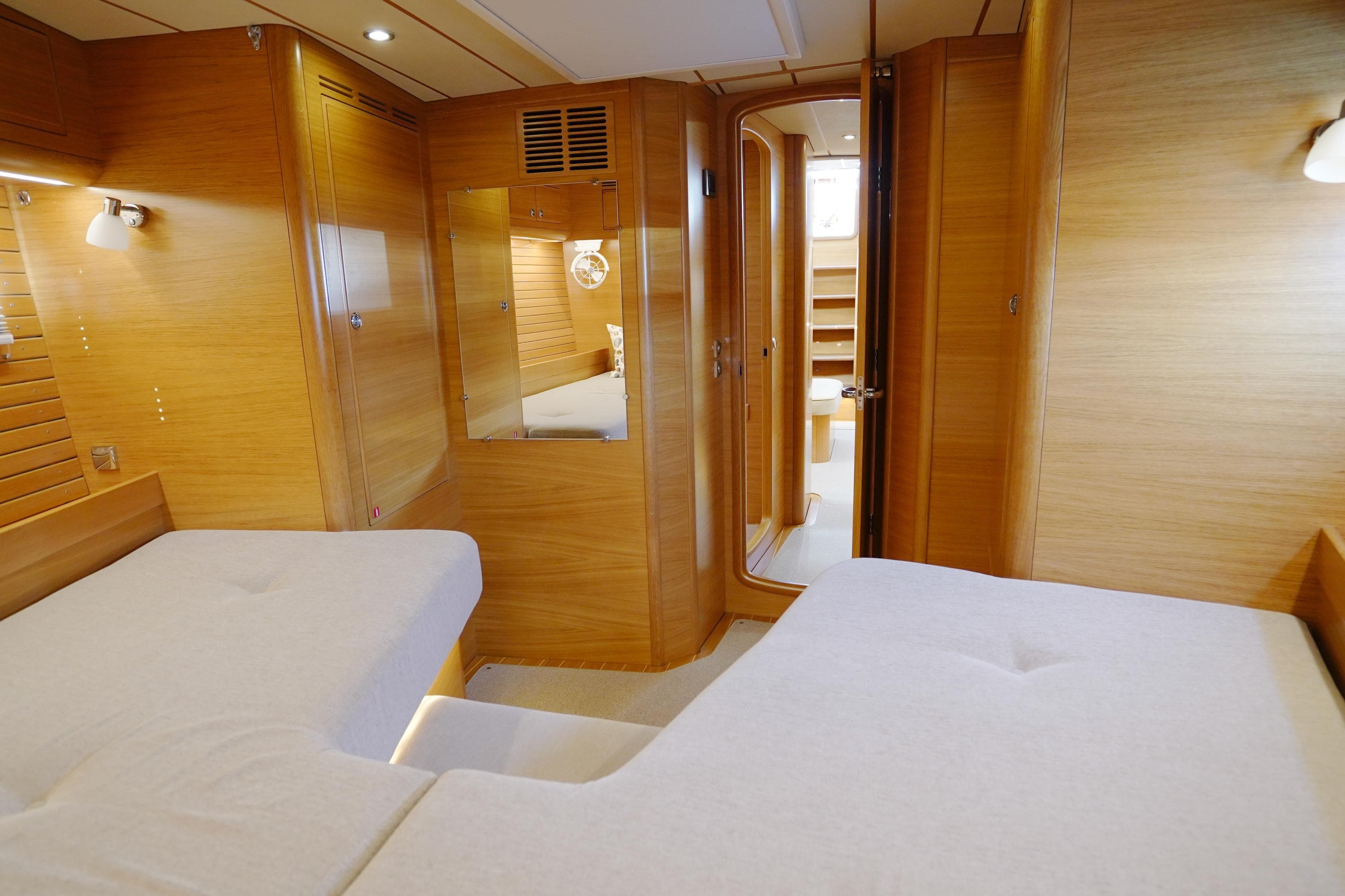 Luxurious interior of 2022 Hallberg-Rassy 57 yacht with wooden finish and cozy bedding.