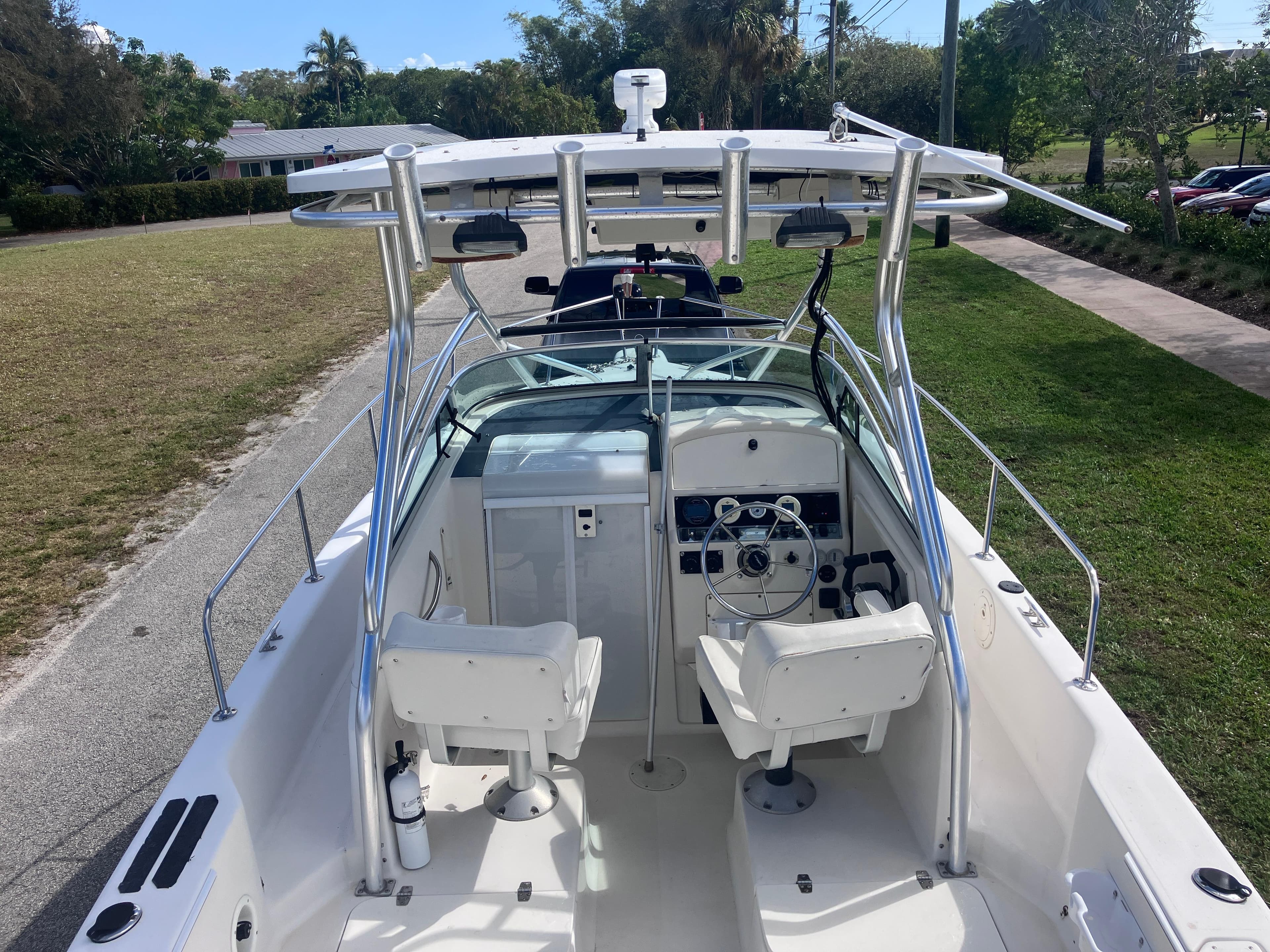 1998 Pro-Line 241 Walkaround boat with dual seats and steering console, parked on grass.