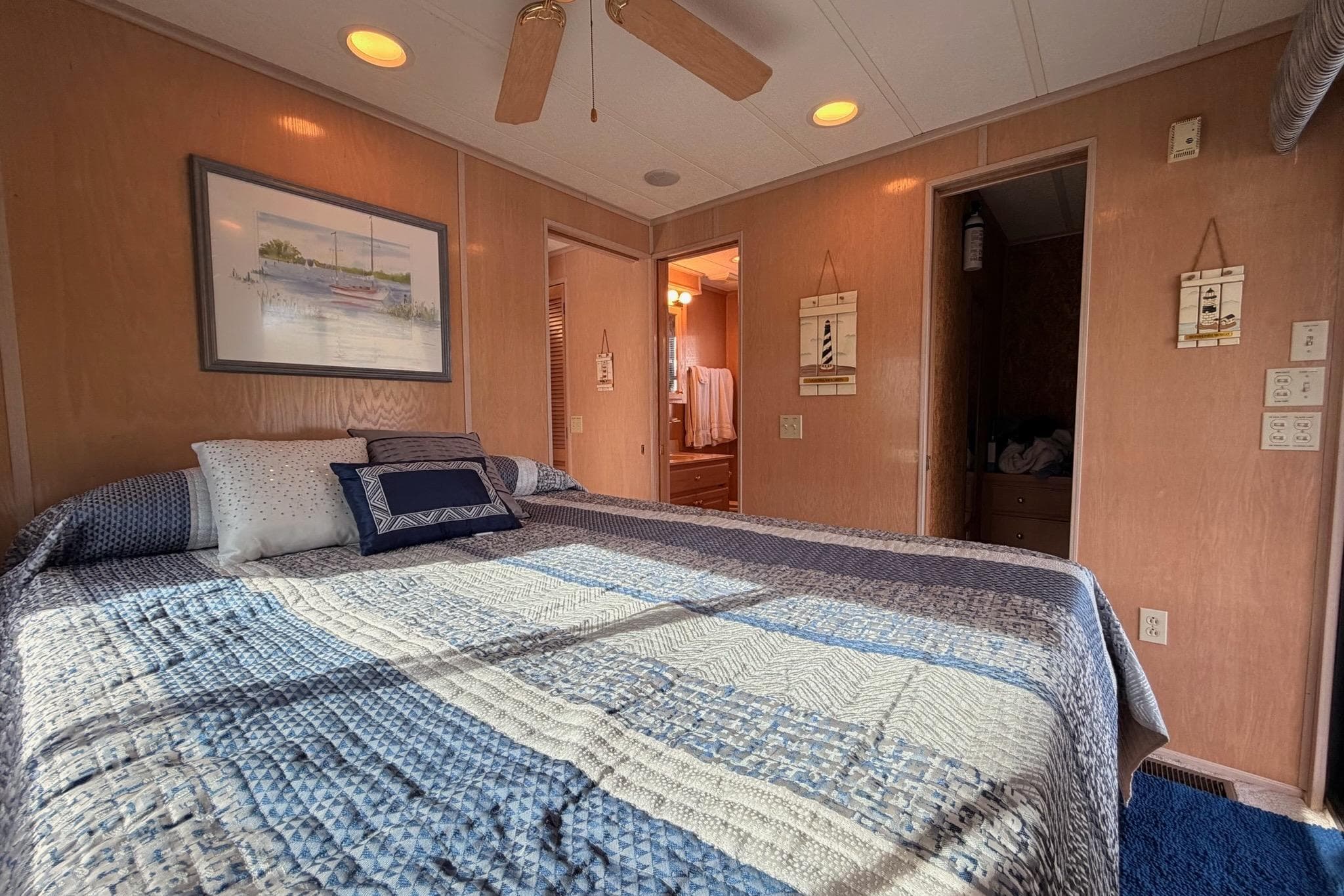 Cozy bedroom in a 2000 Sunstar 16x65 houseboat with nautical decor and quilted bedding.