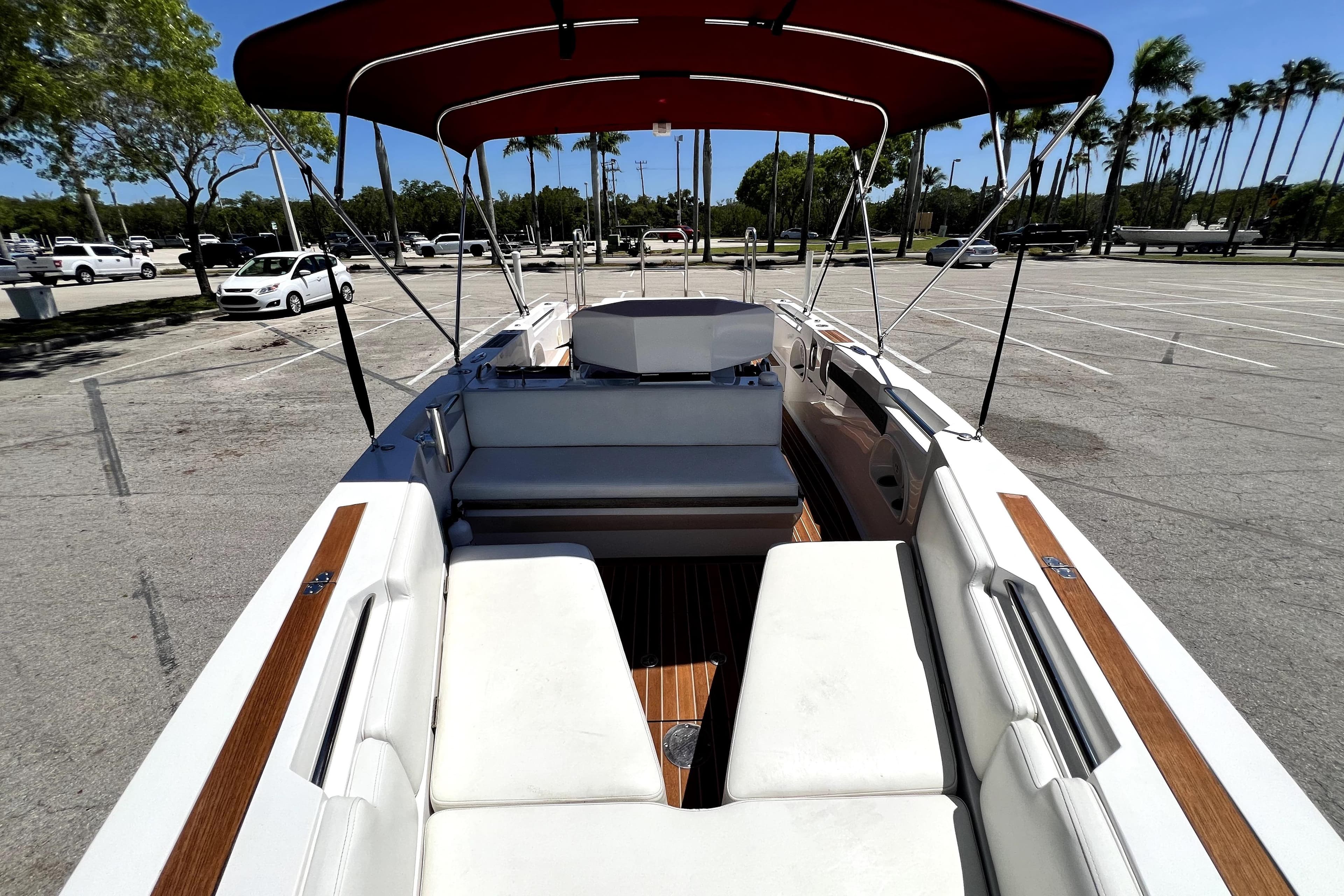 2013 Novurania Chase 23 boat with white seating and red canopy in a parking lot.