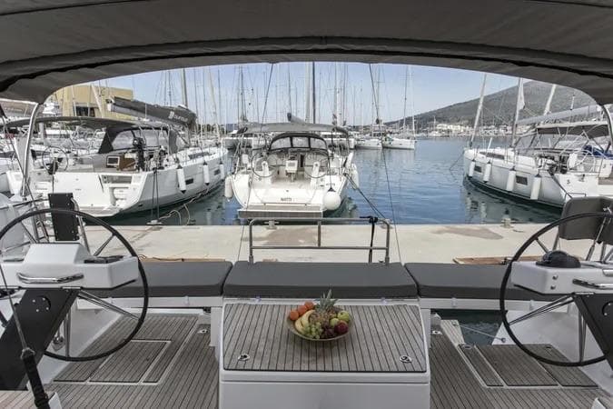 2022 Dufour 530 yacht cockpit with dual steering wheels, docked in a marina.