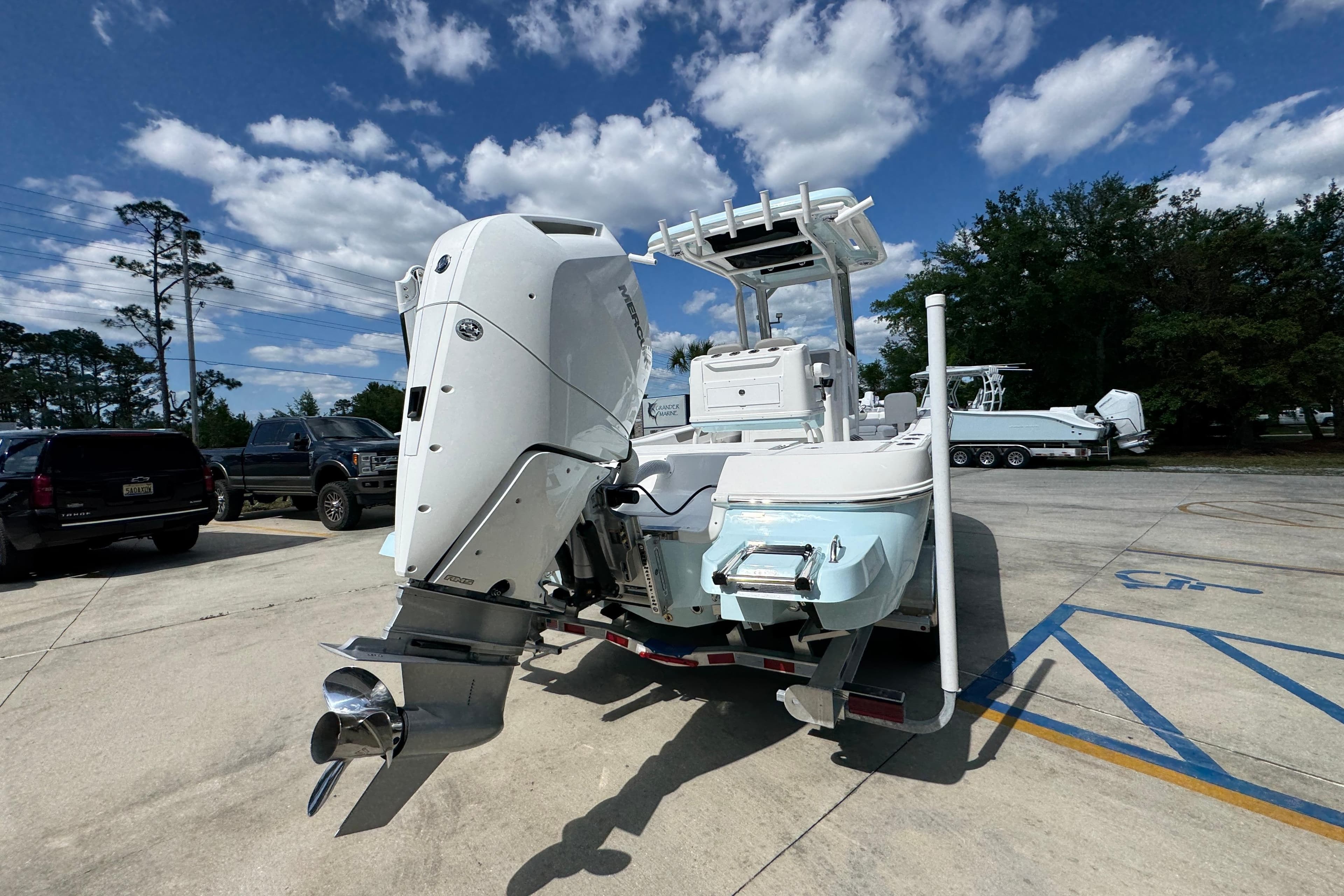 2026 Caymas 26 HB boat with powerful outboard motor in a sunny parking lot.