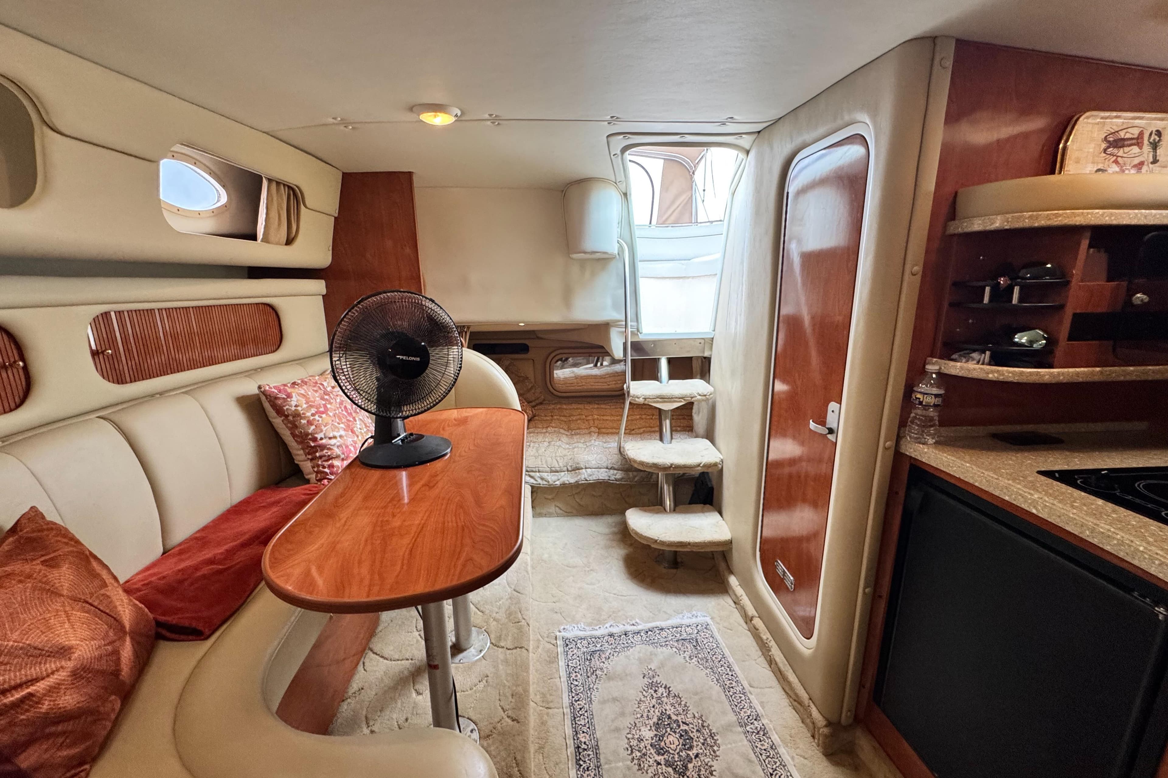 Interior of 2005 Rinker Fiesta Vee 342 boat with cozy seating and kitchenette.