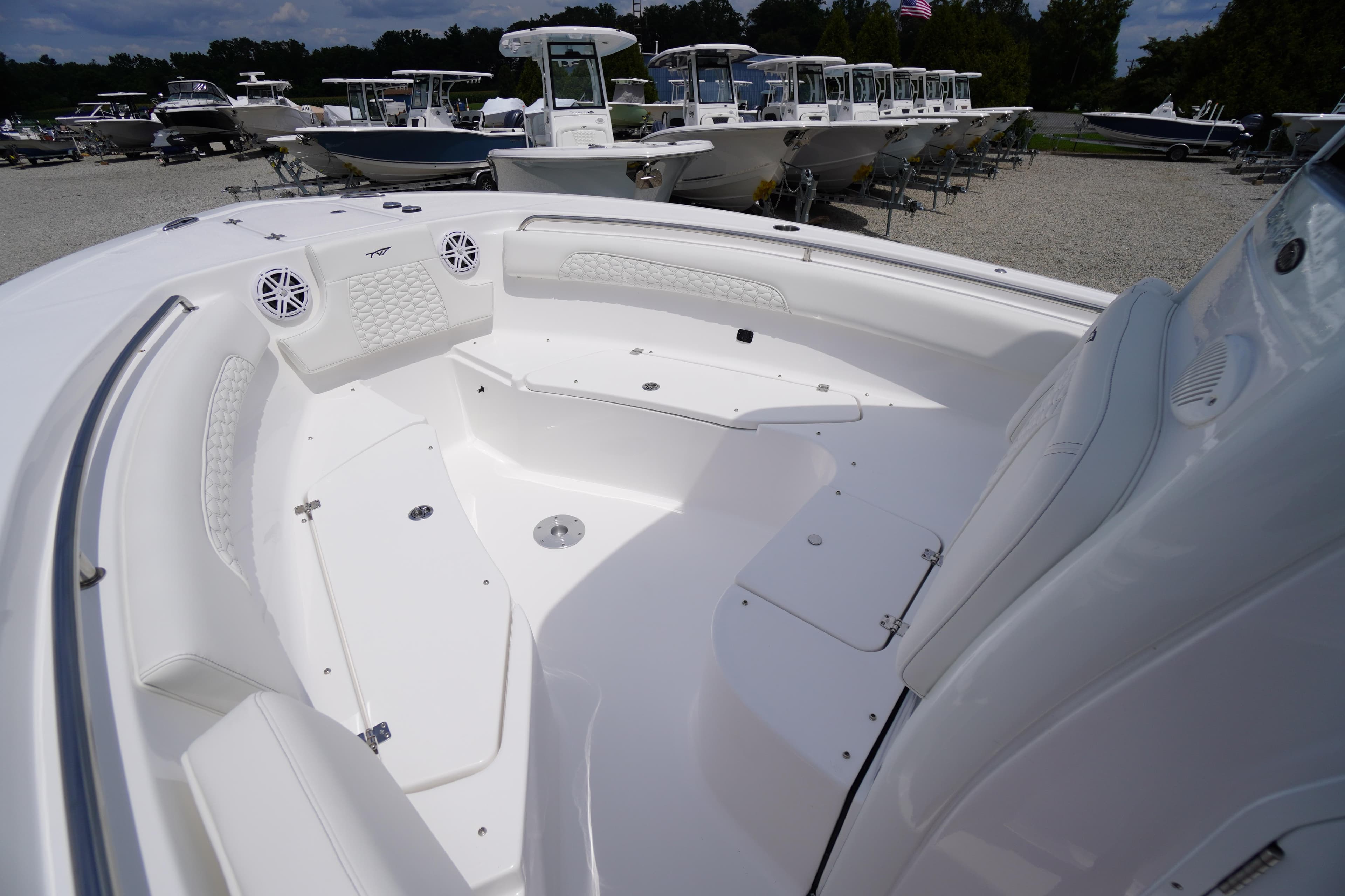 2026 Tidewater 232 SS boat interior with white seating and speakers, docked among other boats.