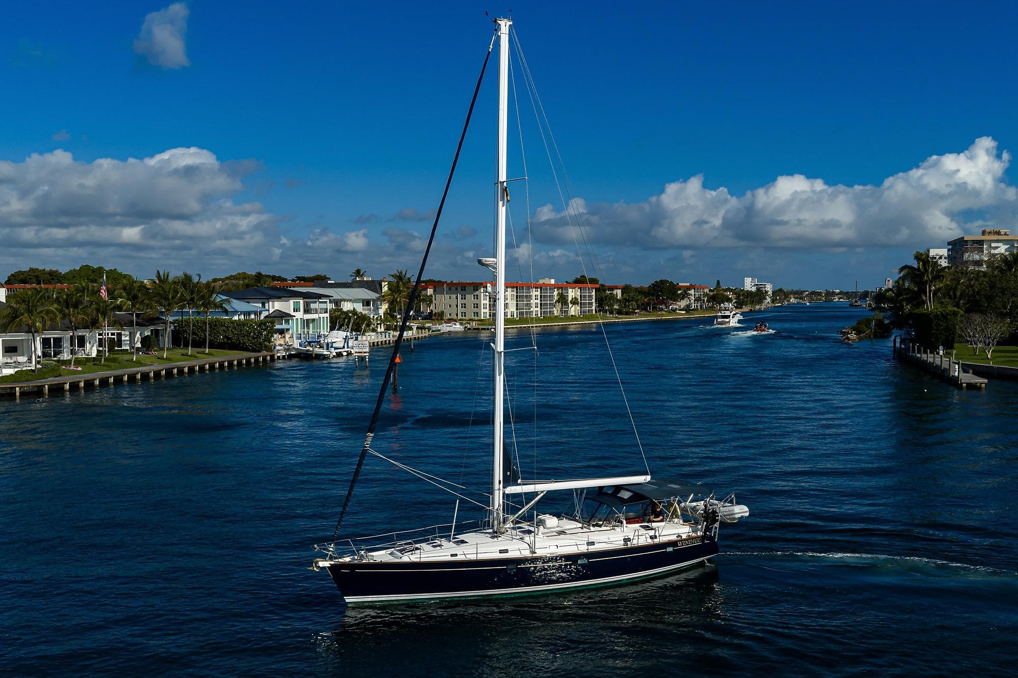 Sailing yacht Beneteau 50 (2003) cruising on a scenic waterway under a clear blue sky.