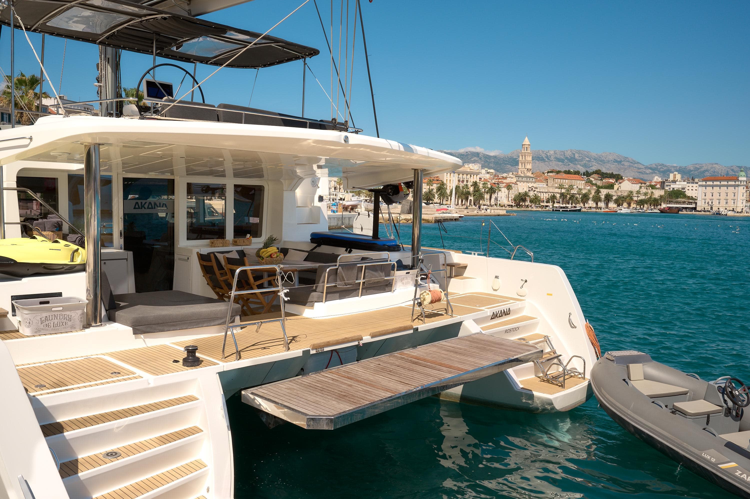 2019 Lagoon 52 F yacht docked in a scenic harbor with cityscape background.