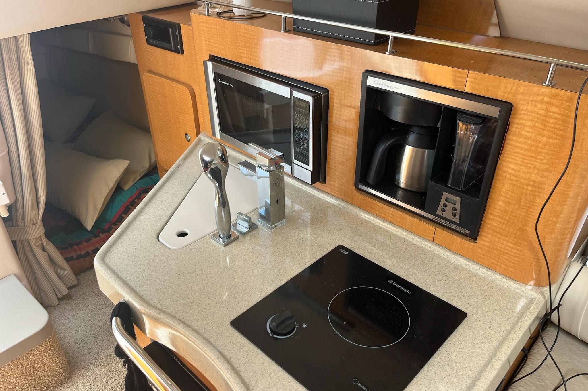 Compact kitchen area in a 2011 Larson Carbiro 240 boat with microwave and coffee maker.