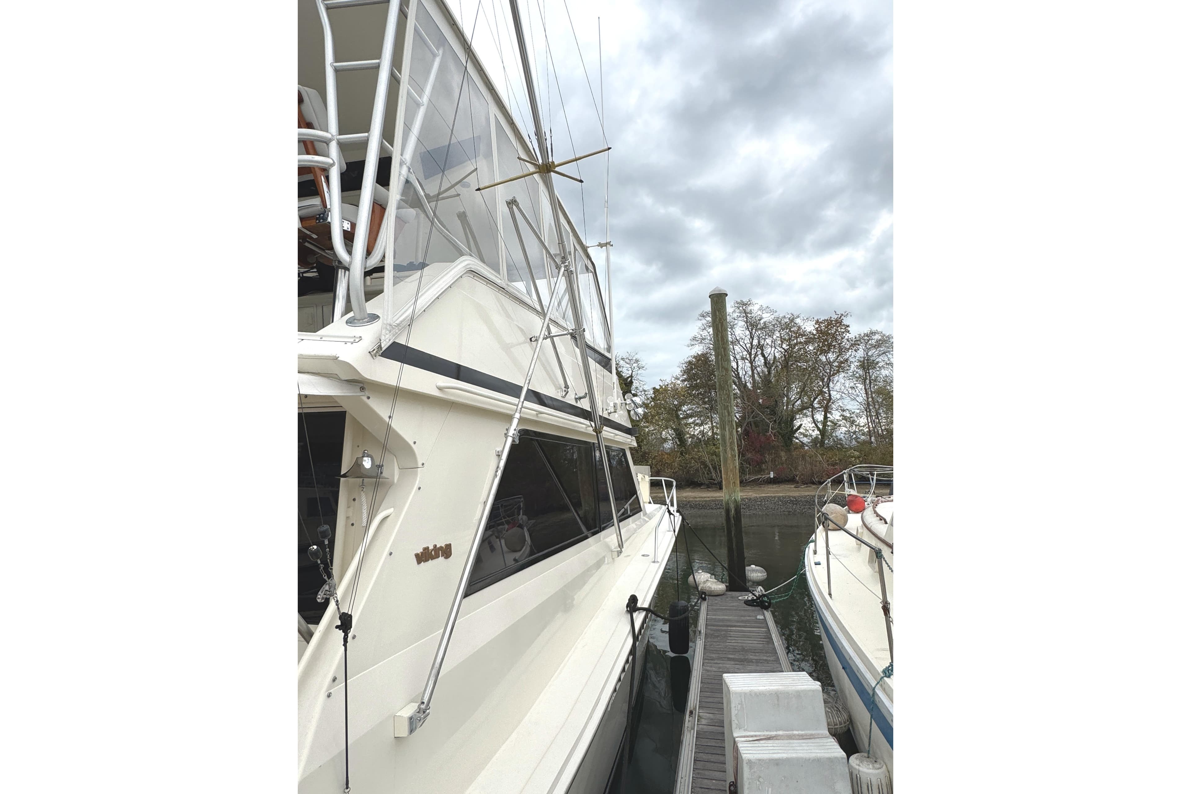 1991 Viking 53 Convertible yacht docked beside another boat under cloudy skies.