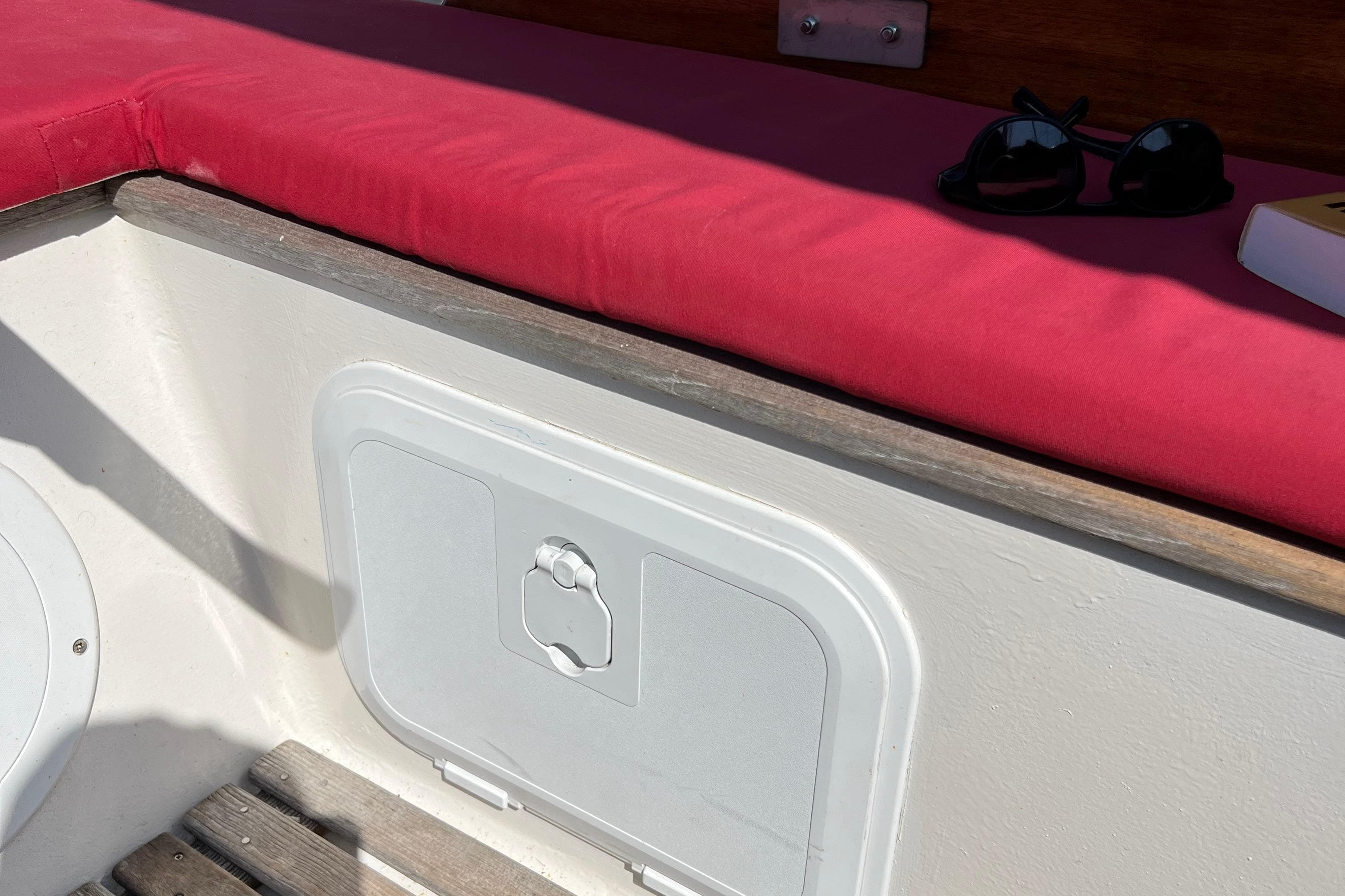 Interior of 1980 EUROVOILE cotre breton with red cushion and sunglasses.