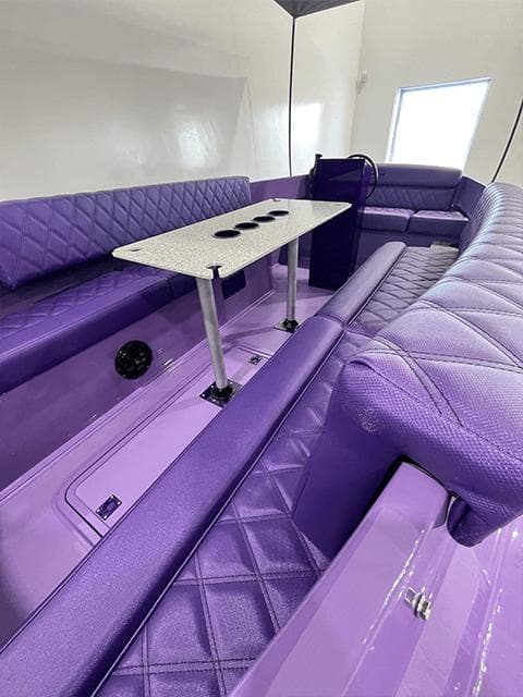 Luxurious purple interior of 2023 Vision Marine Fantail 217 boat with seating and table.