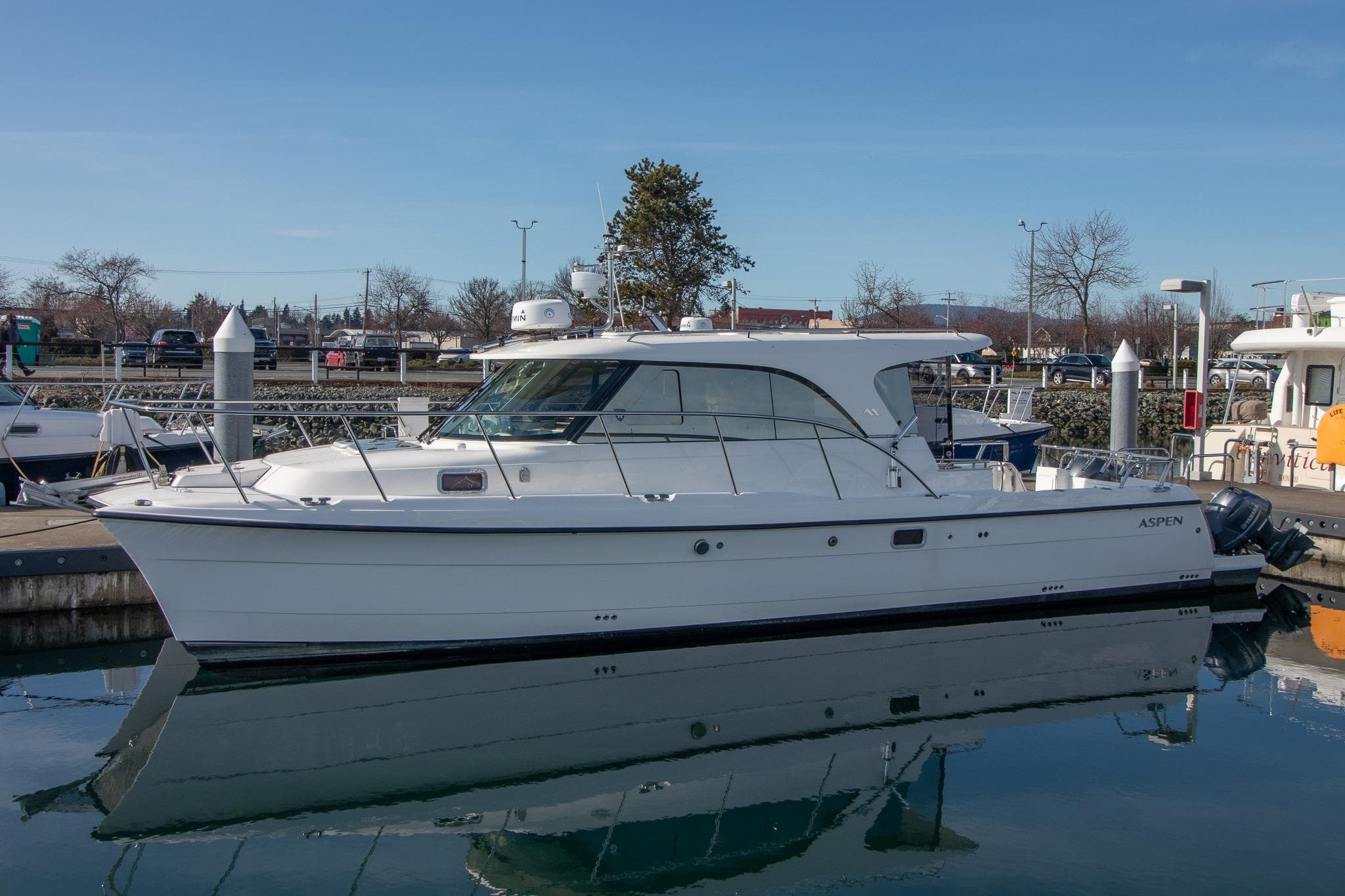 2022 Aspen C107 boat docked in a marina, reflecting on calm water.