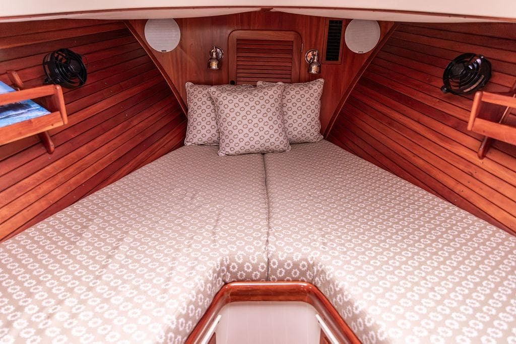 2004 Hinckley Picnic Boat EP cabin interior with cozy bedding and wooden paneling.