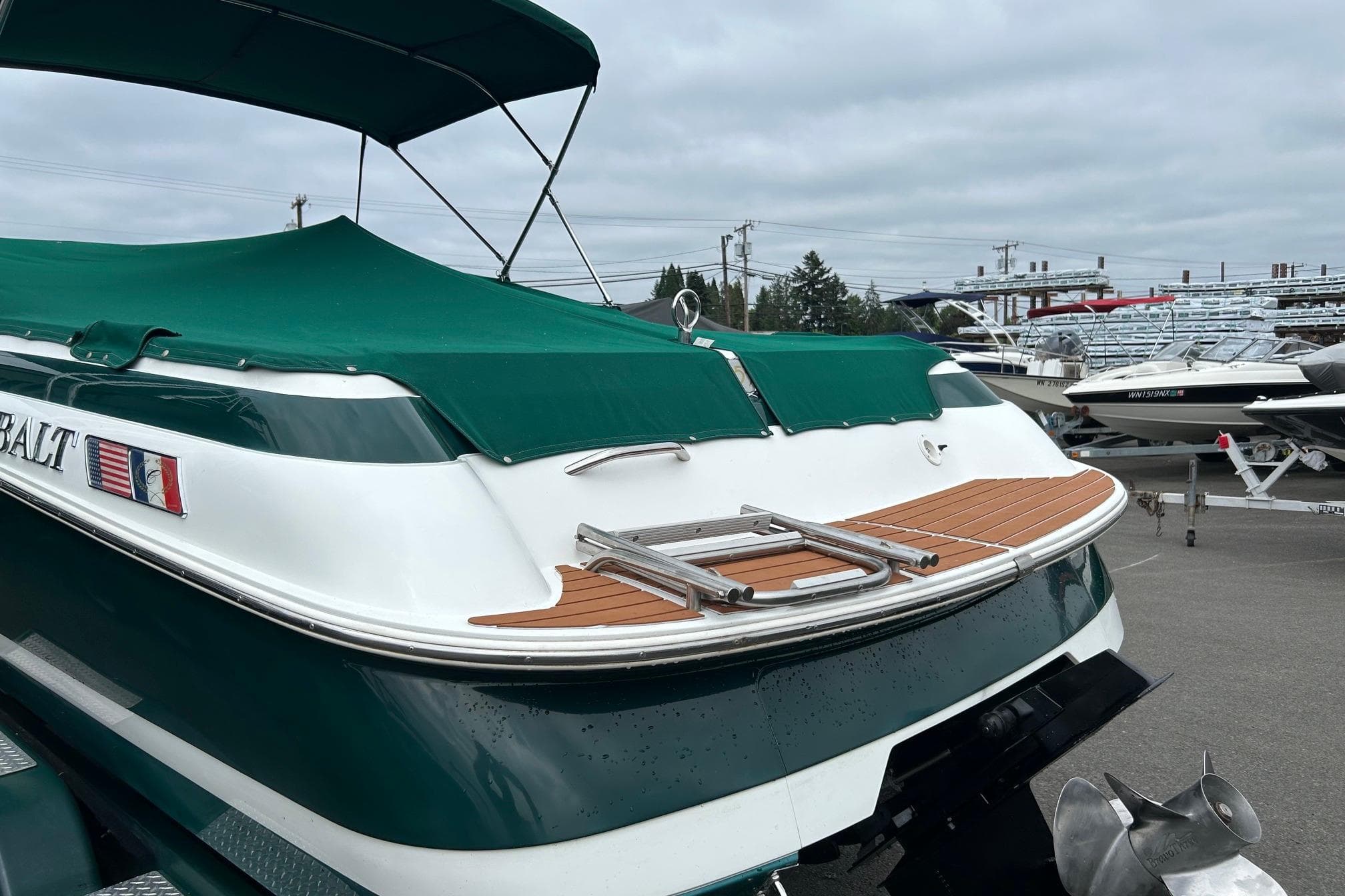 1995 Cobalt 253 boat with green cover and swim platform, parked in marina.