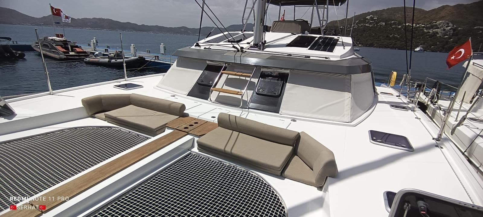 2021 Nautitech 46 Fly catamaran with spacious deck and seating, docked in a scenic marina.