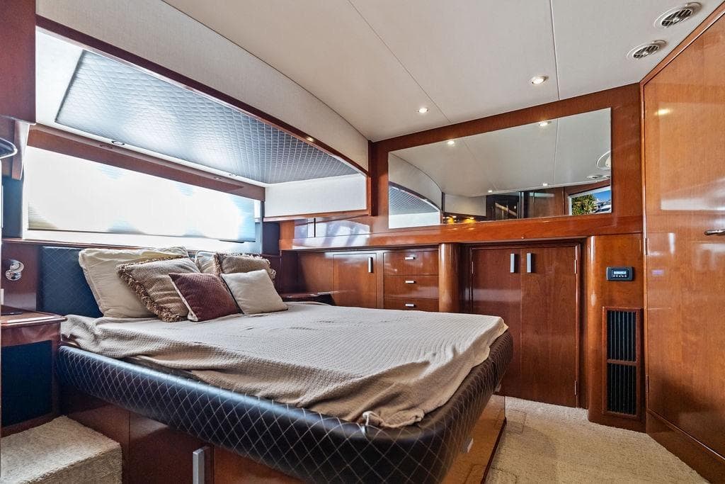 Luxurious 2009 Carver 56 Voyager SE yacht bedroom with elegant wood finishes and plush bedding.