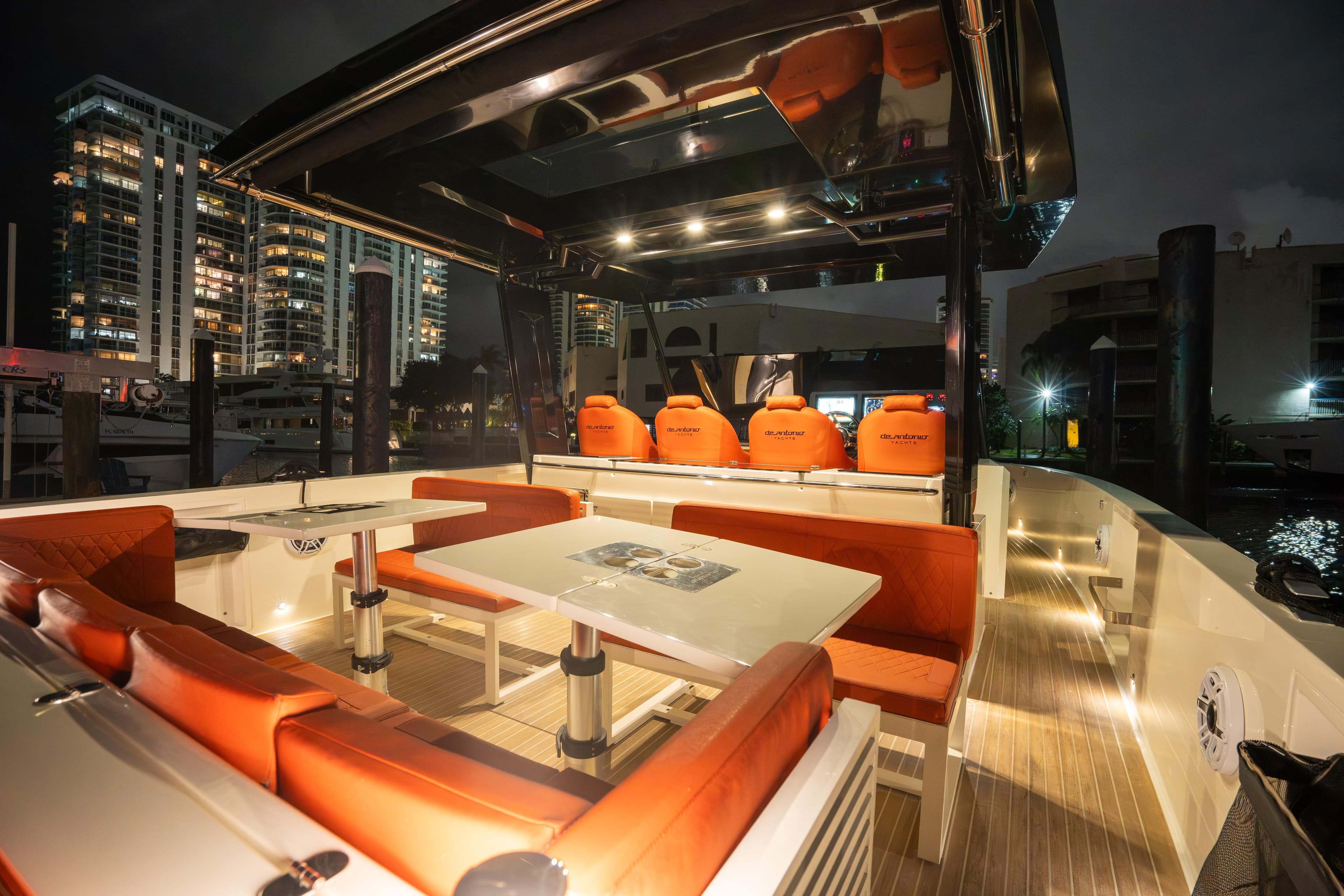 2023 De Antonio Yachts D42 Open, luxurious deck with orange seating, city skyline at night.
