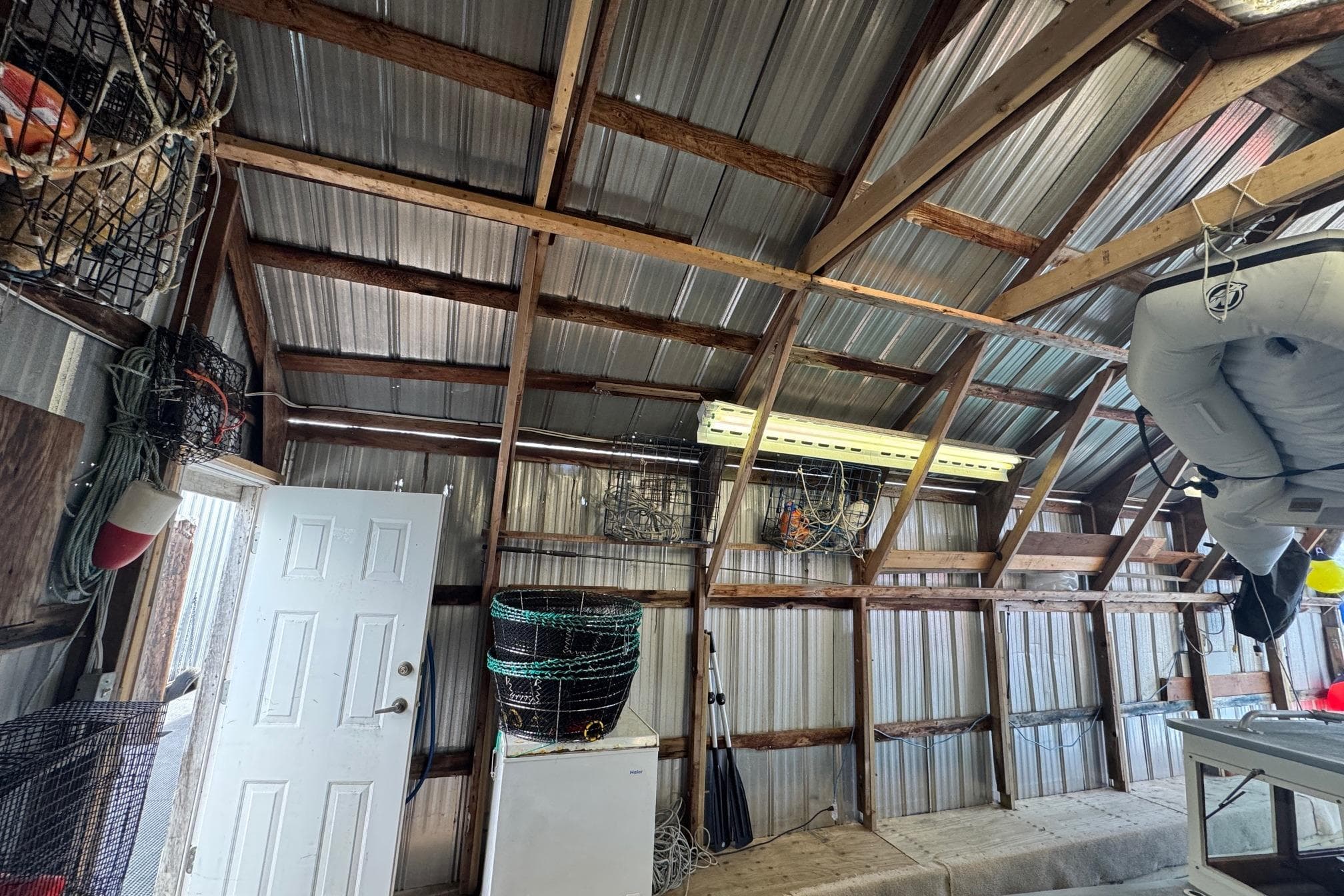 Interior of a 1990 custom boathouse with fishing gear and inflatable boat.