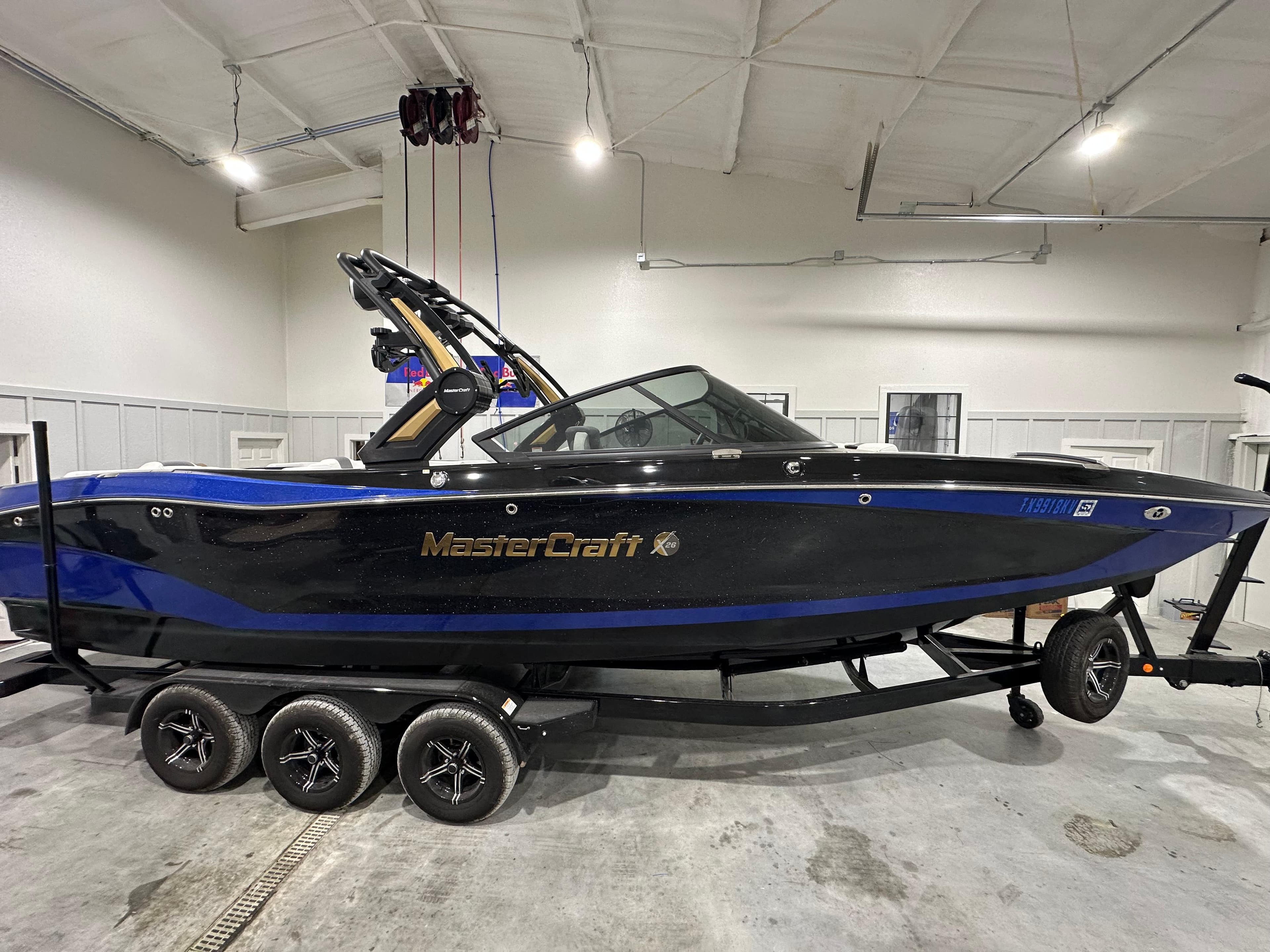 2024 MasterCraft X26 boat in showroom, black and blue design, on a trailer.