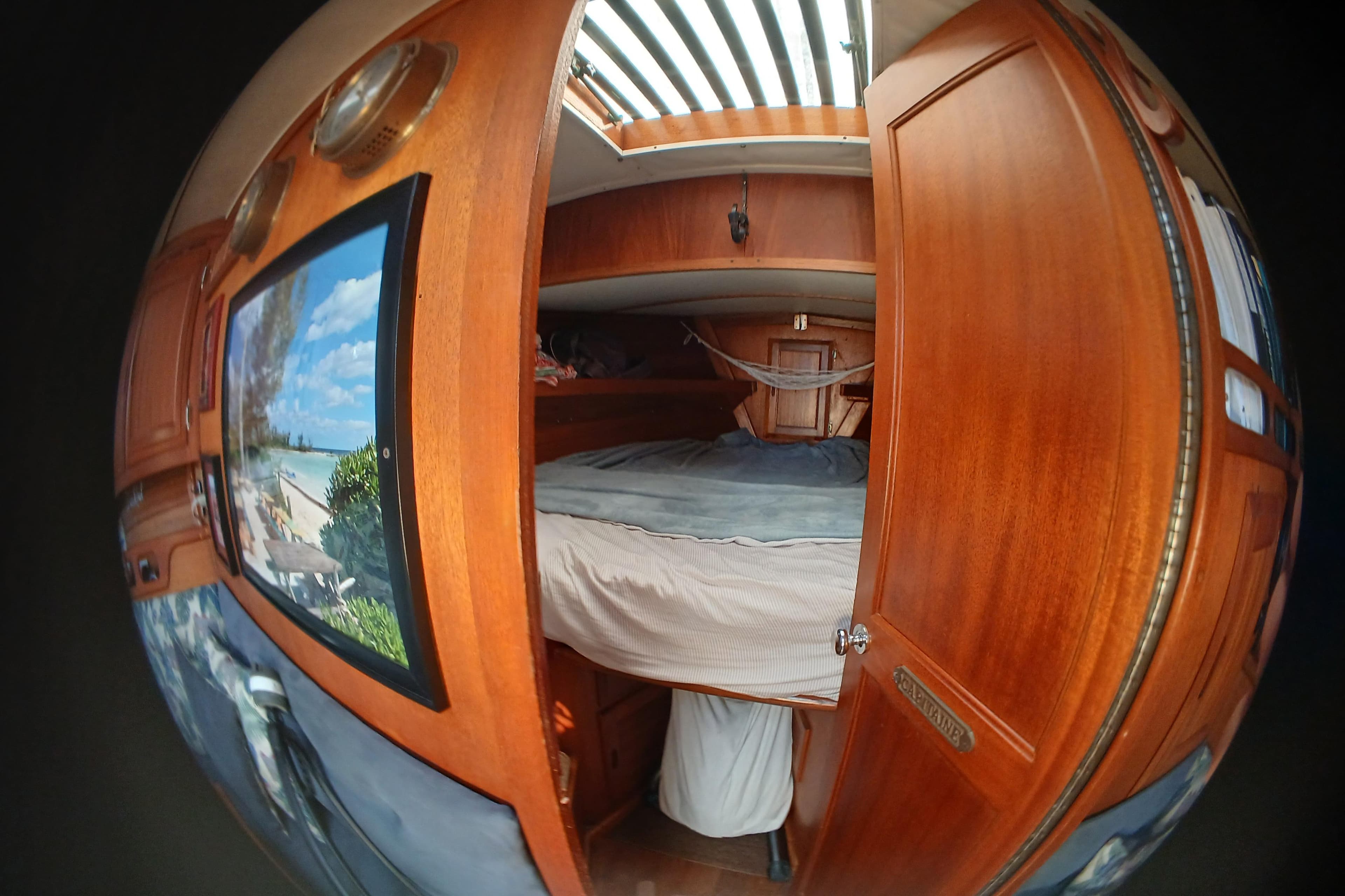 Cozy cabin interior of 1977 Ericson 36 C sailboat with wooden furnishings and skylight.