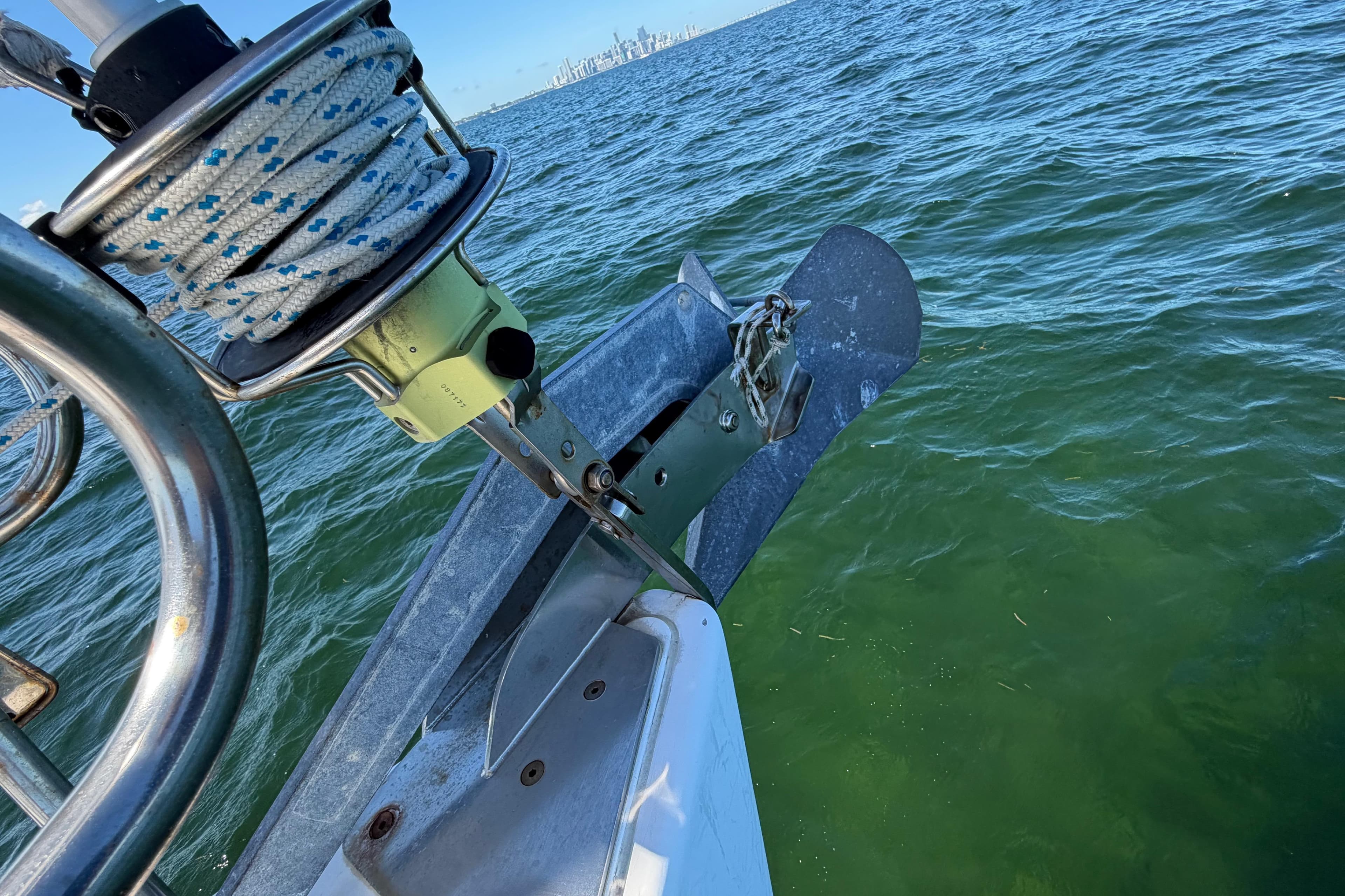 Bow of 2008 Beneteau Oceanis 40 sailboat with anchor over green water.