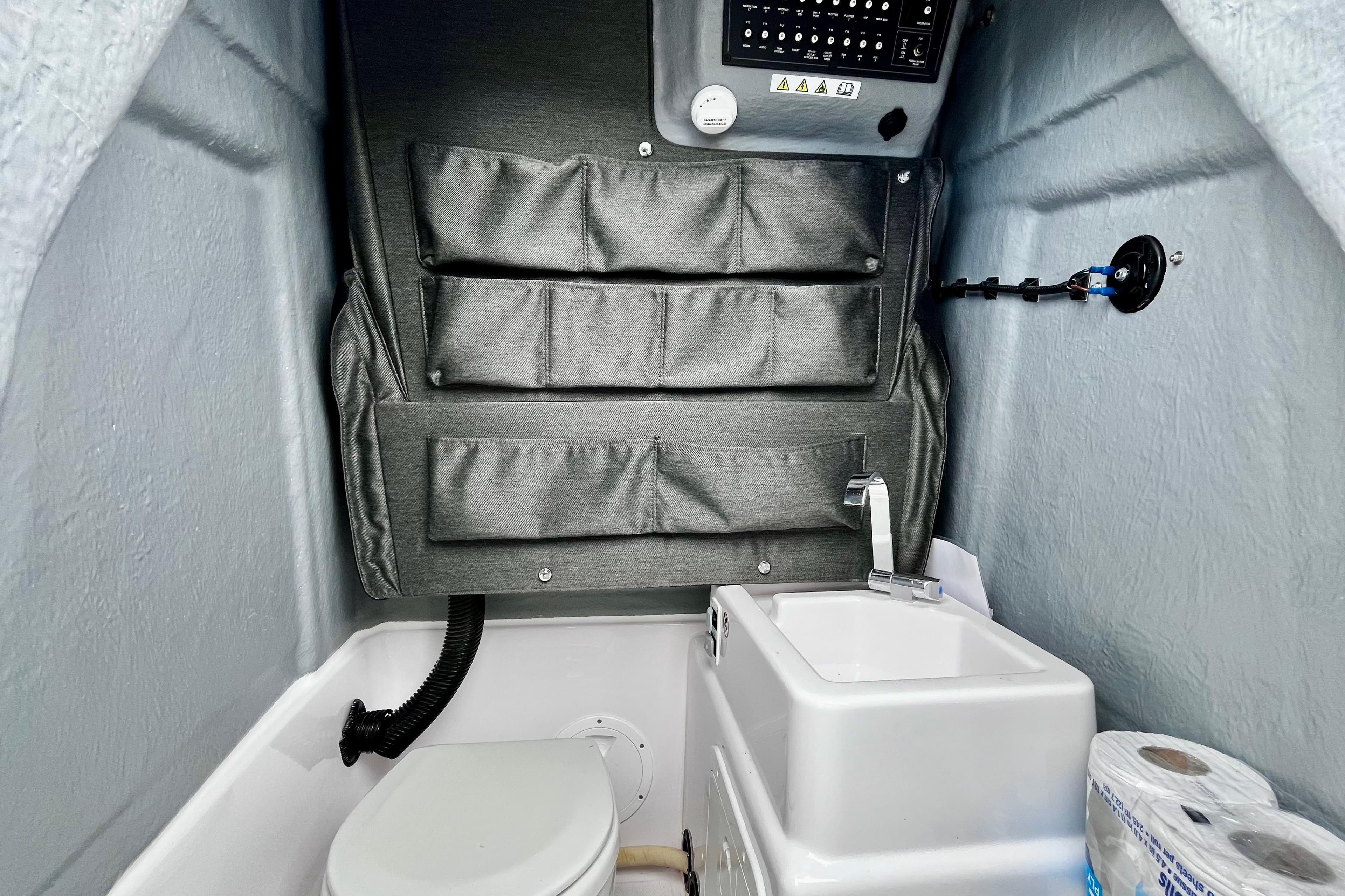 Interior of 2023 Axopar 22 T-Top boat featuring compact bathroom with sink and storage.