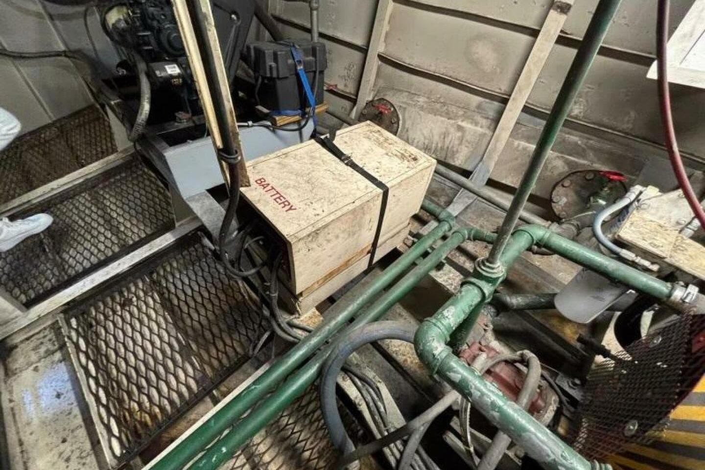 Engine room of a 1984 Custom Paddle Wheel boat with visible battery and machinery.
