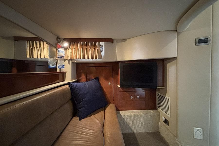 Interior of 2006 Sea Ray 44 Sundancer yacht with sofa, TV, and wooden cabinetry.