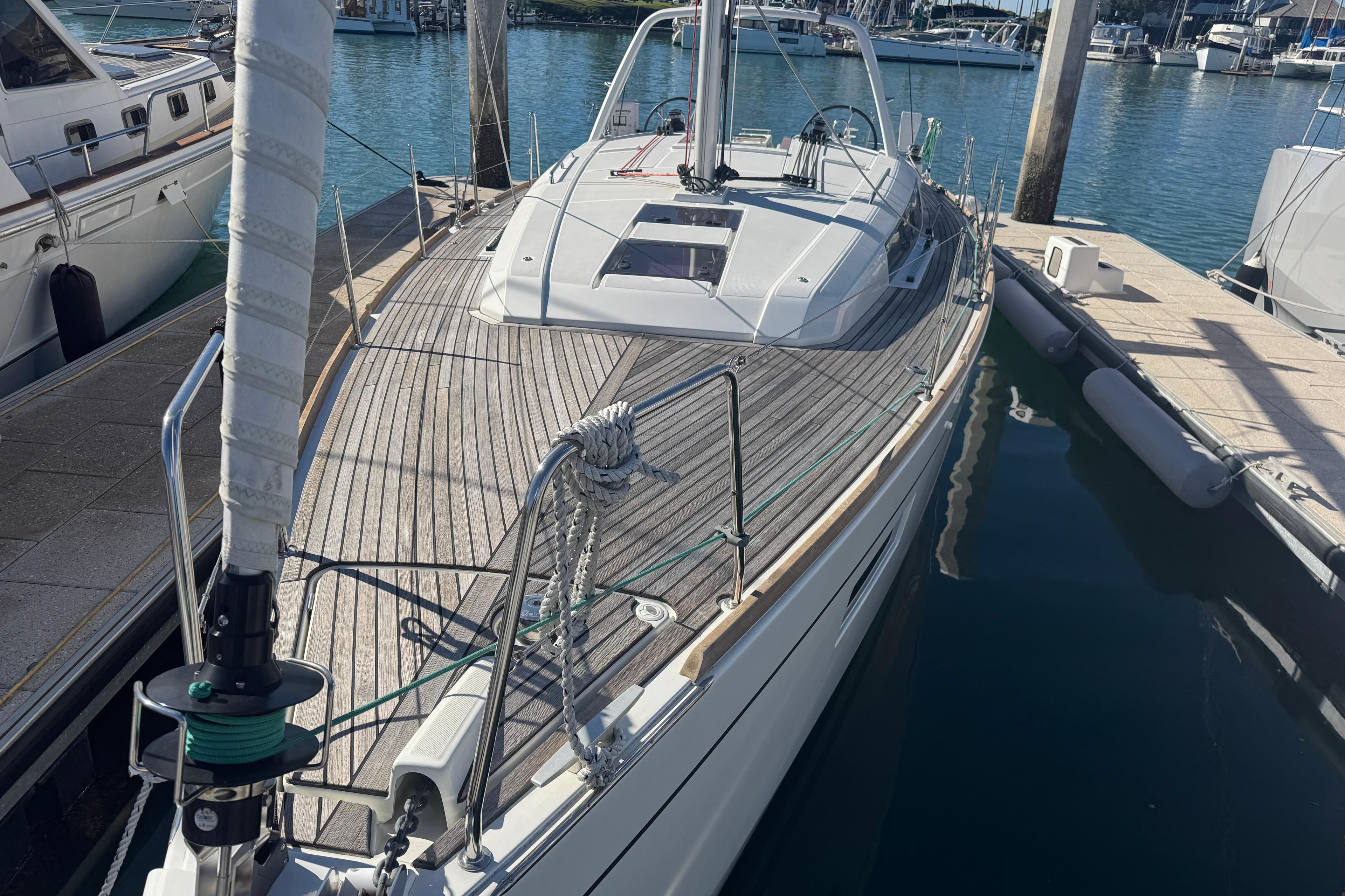 2023 Beneteau Oceanis 38.1 yacht docked in marina, showcasing sleek design and wooden deck.