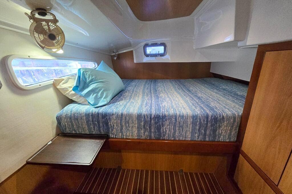 Cozy cabin interior of 2006 Dolphin 460 yacht with bed, window, and fan.
