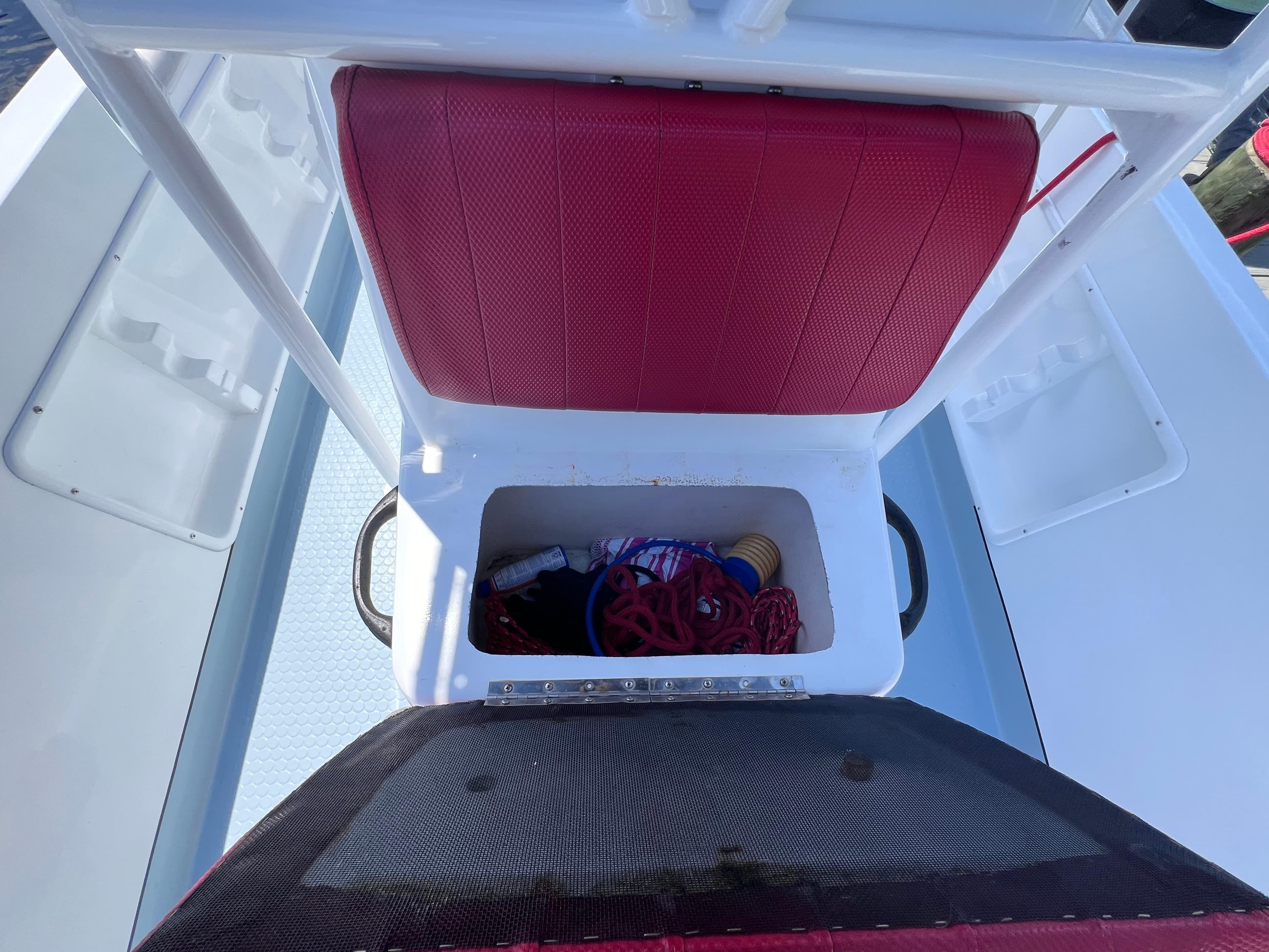 Red seat storage compartment on Concept 23 boat, year 2000, with ropes and accessories.
