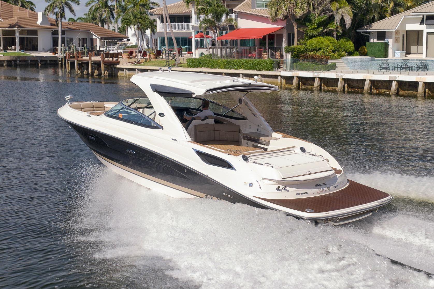 2016 Sea Ray 350 SLX cruising on a scenic waterfront with luxury homes.