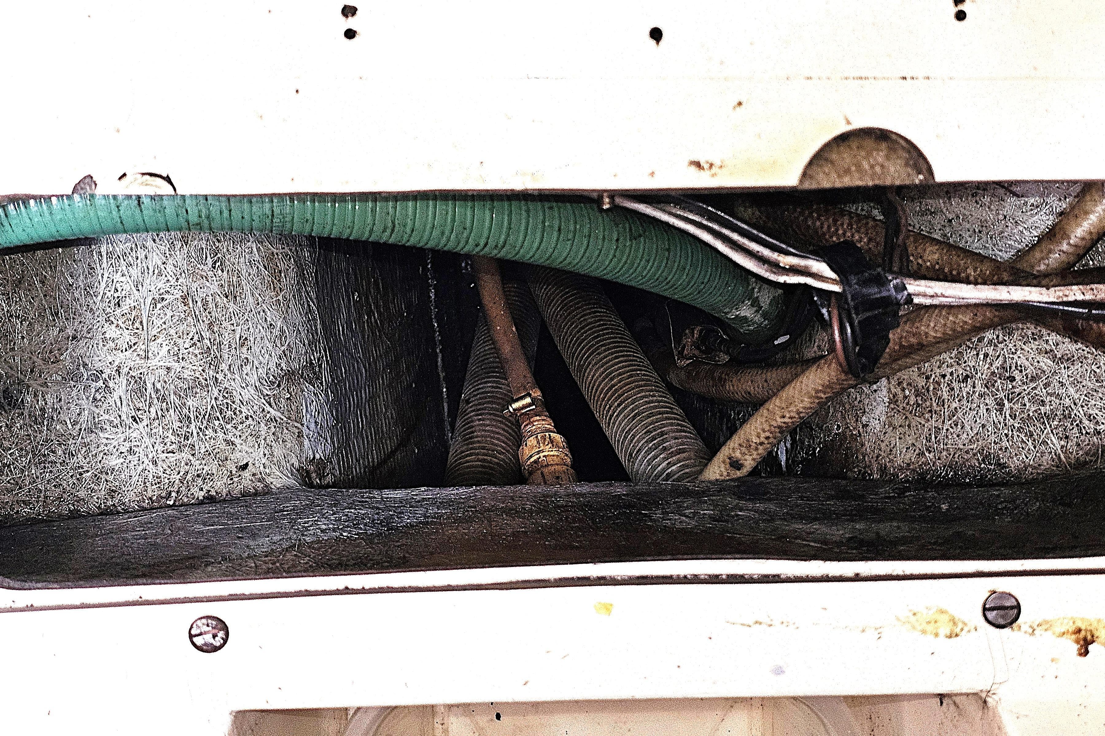 Engine compartment of a 1992 Northshore Yachts Vancouver 34, showing hoses and wiring.