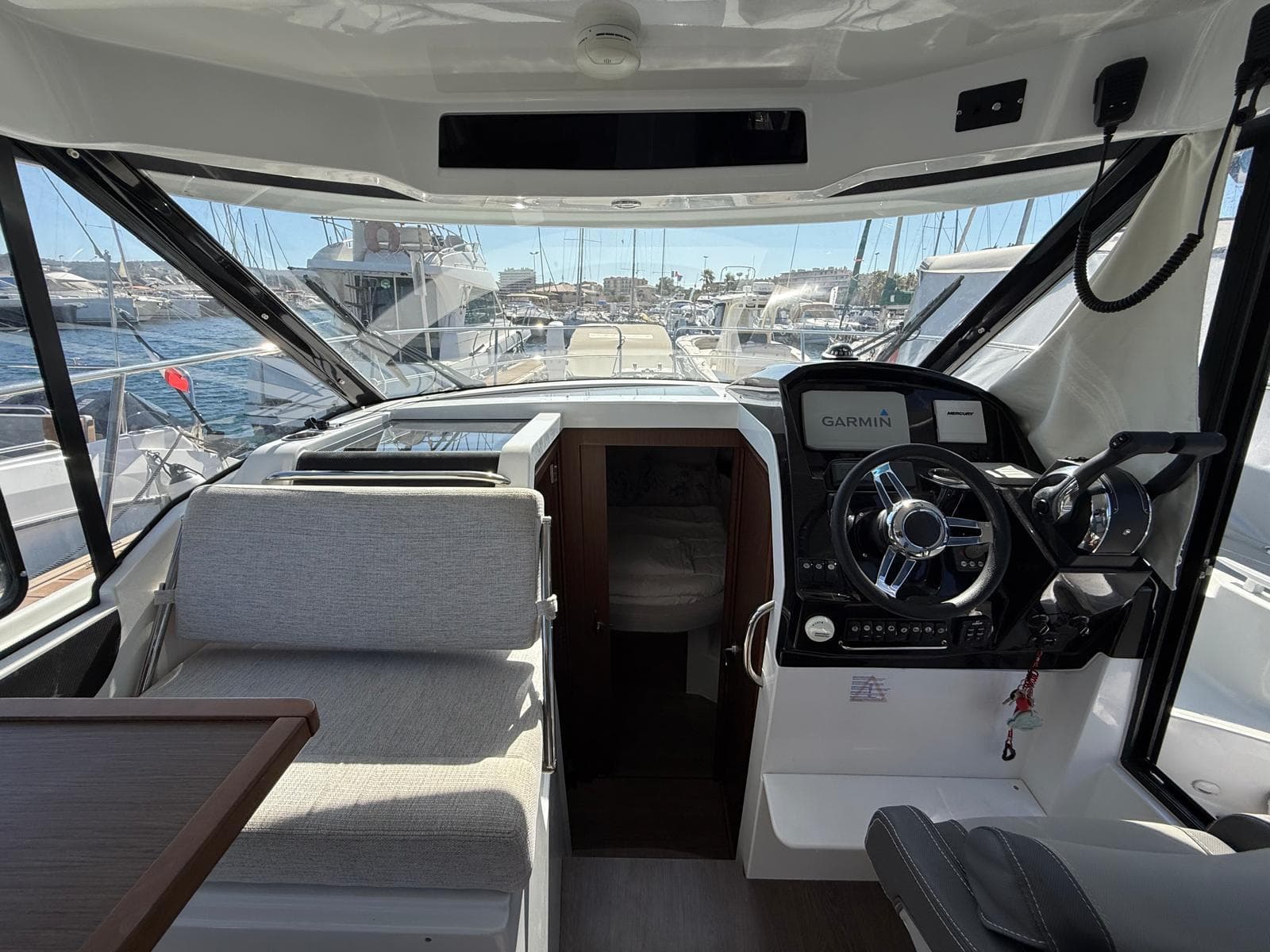 Interior of 2022 Jeanneau Merry Fisher 895 boat with steering wheel and navigation system.
