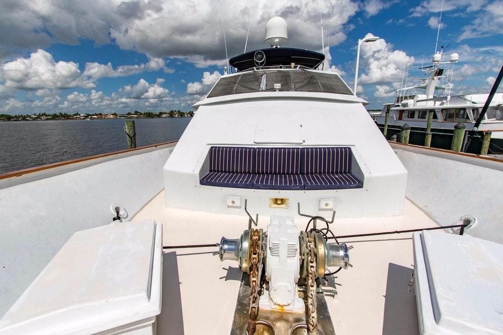1983 Benetti Custom Lloyds M.Y. yacht deck with seating, docked under a partly cloudy sky.