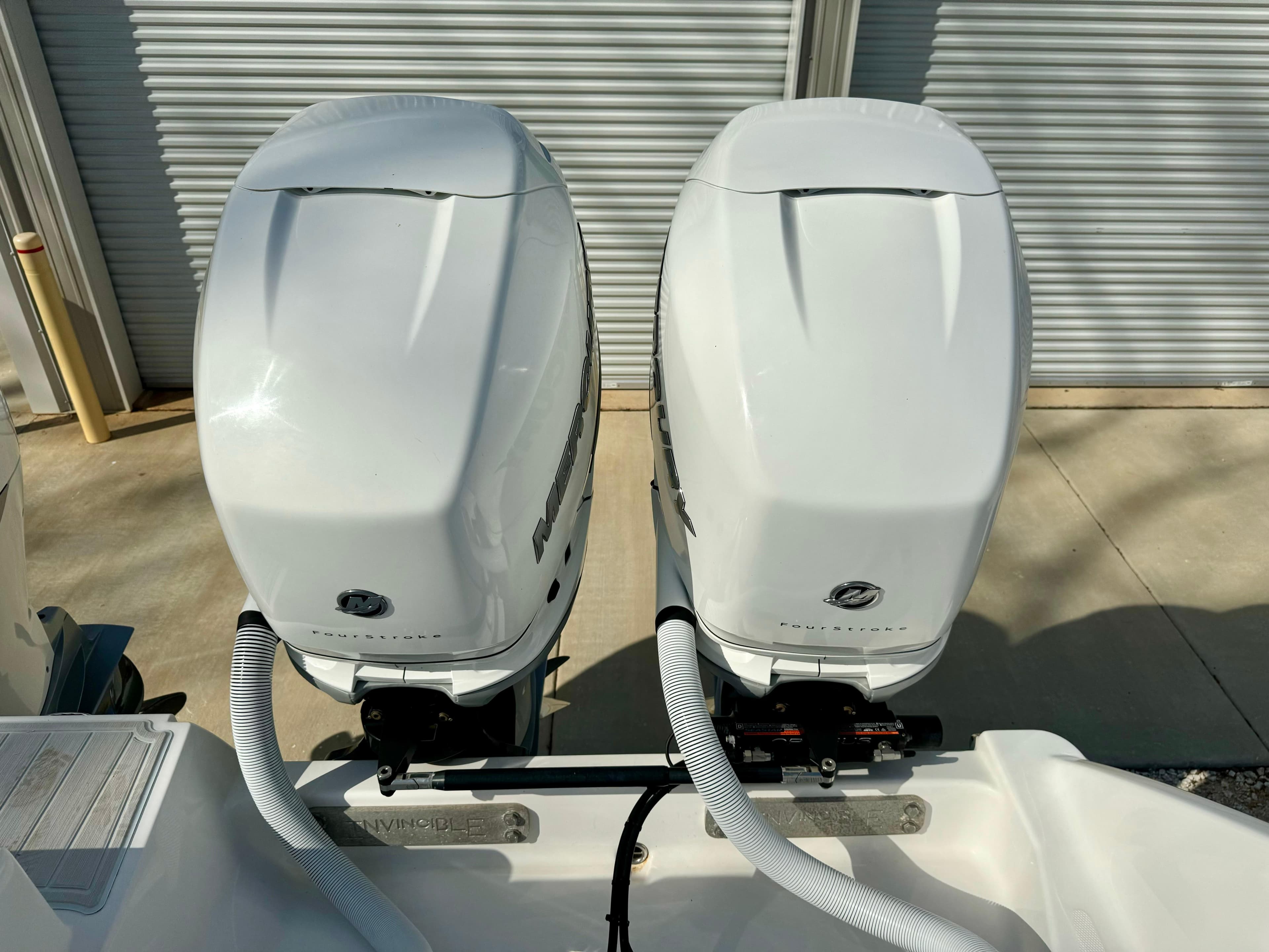 Twin outboard engines on a 2020 Invincible 37 Catamaran, parked near a garage.