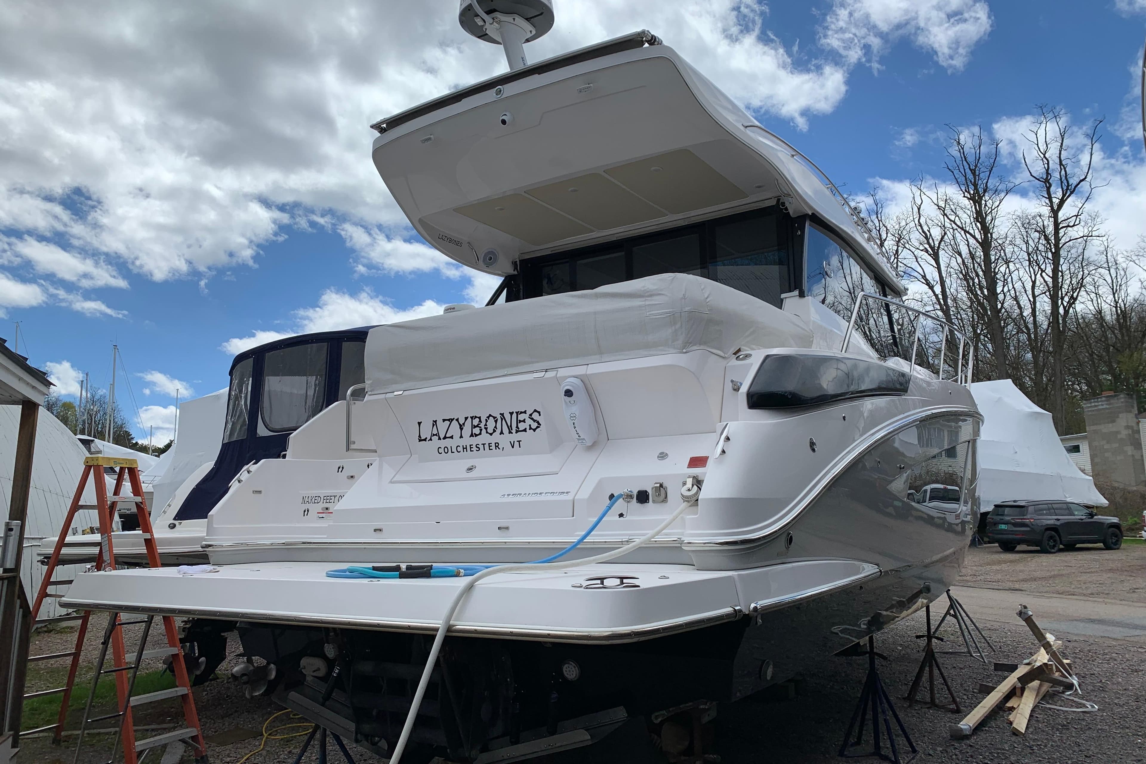2019 Regal 42 Grande Coupe yacht on land, named "Lazybones," under a cloudy sky.