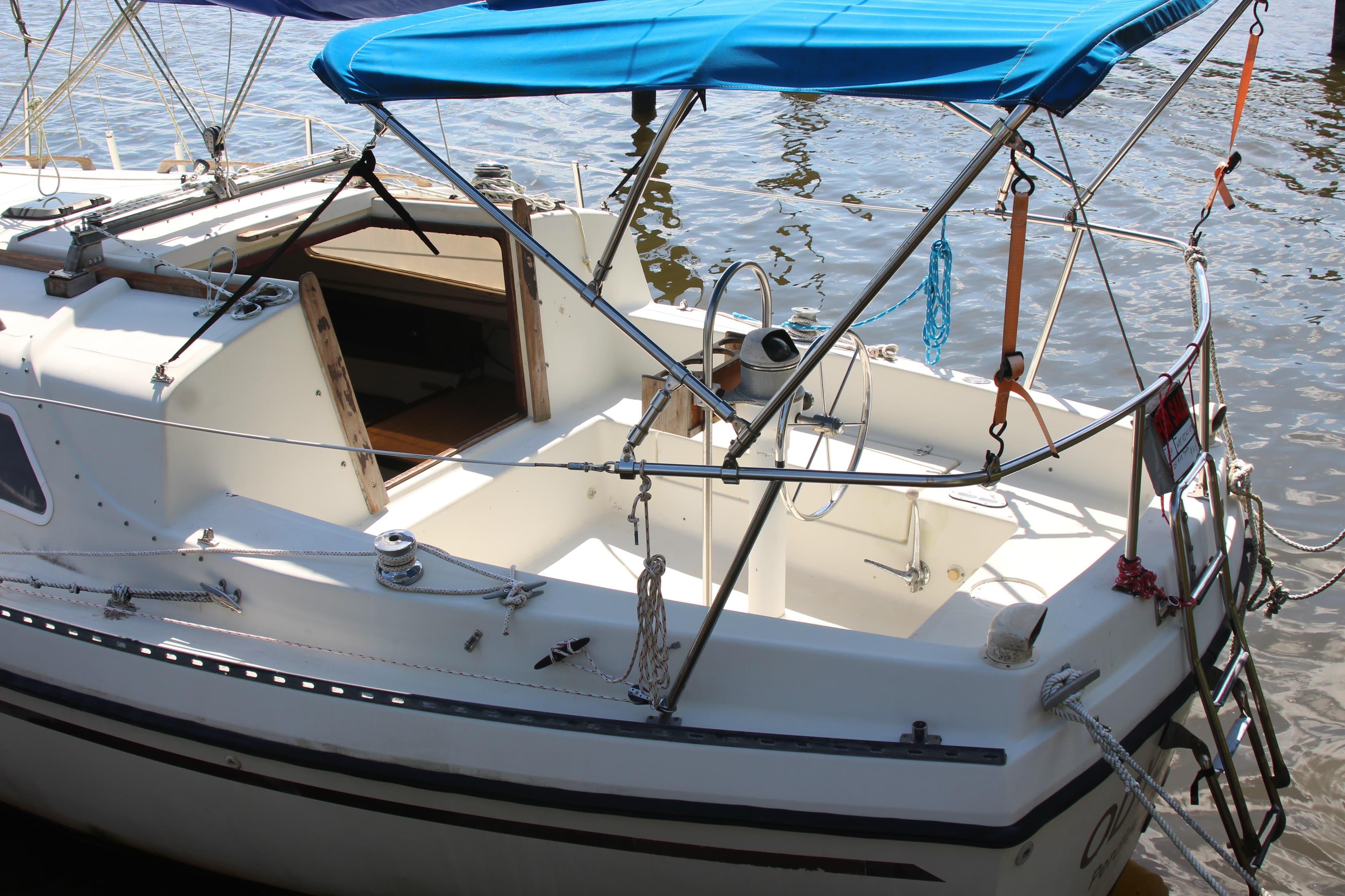 1980 Watkins MONOHULL sailboat with blue canopy, docked on calm water.