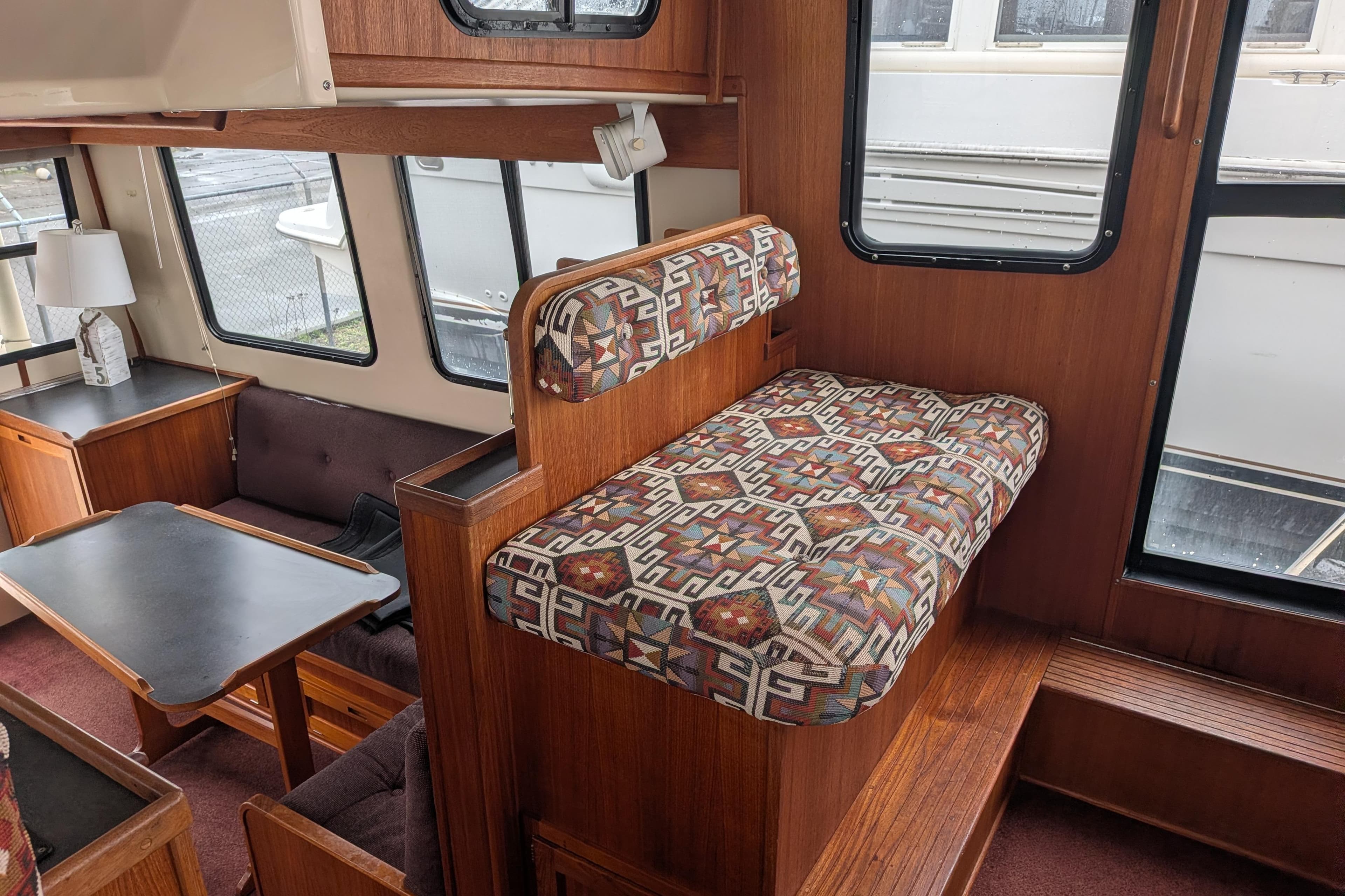 Interior of a 2000 Nordic Tug 37, featuring patterned seating and wooden furnishings.