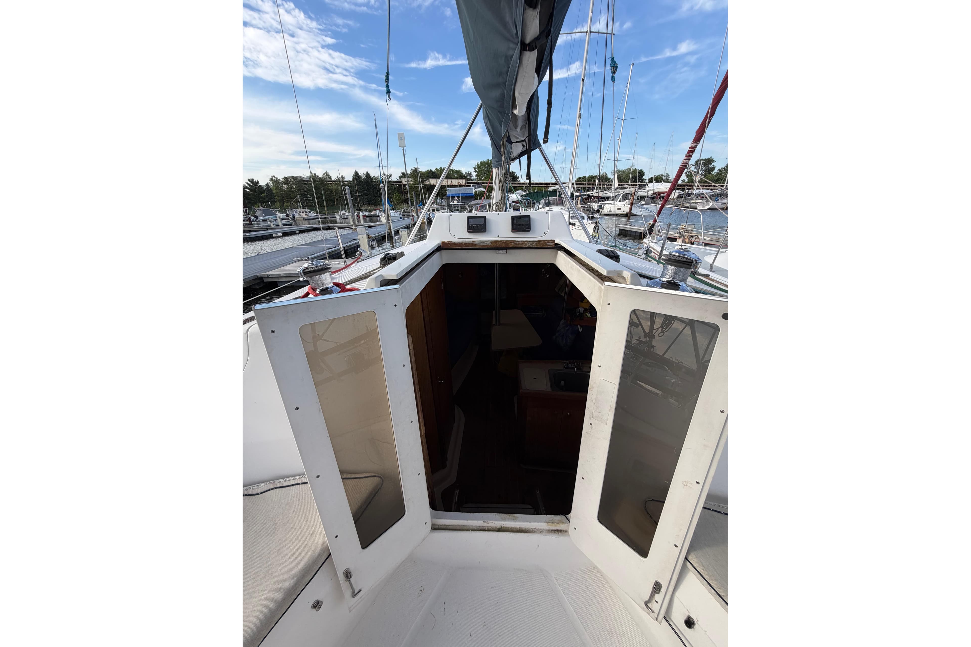 Hunter 310 sailboat cockpit view, 2000 model, docked at marina under blue sky.