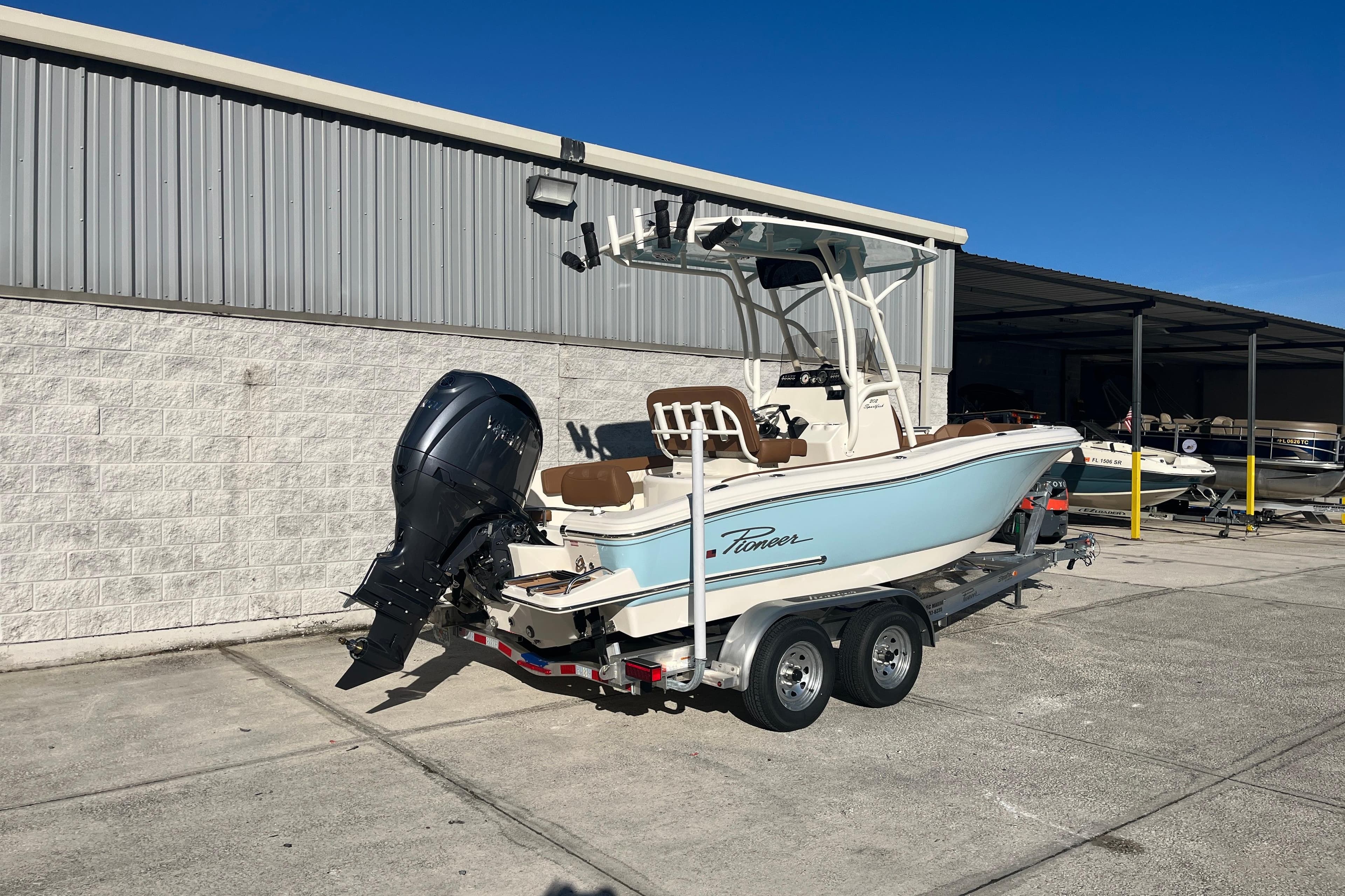 2026 Pioneer 202 Sportfish boat on trailer, parked outdoors near a building.